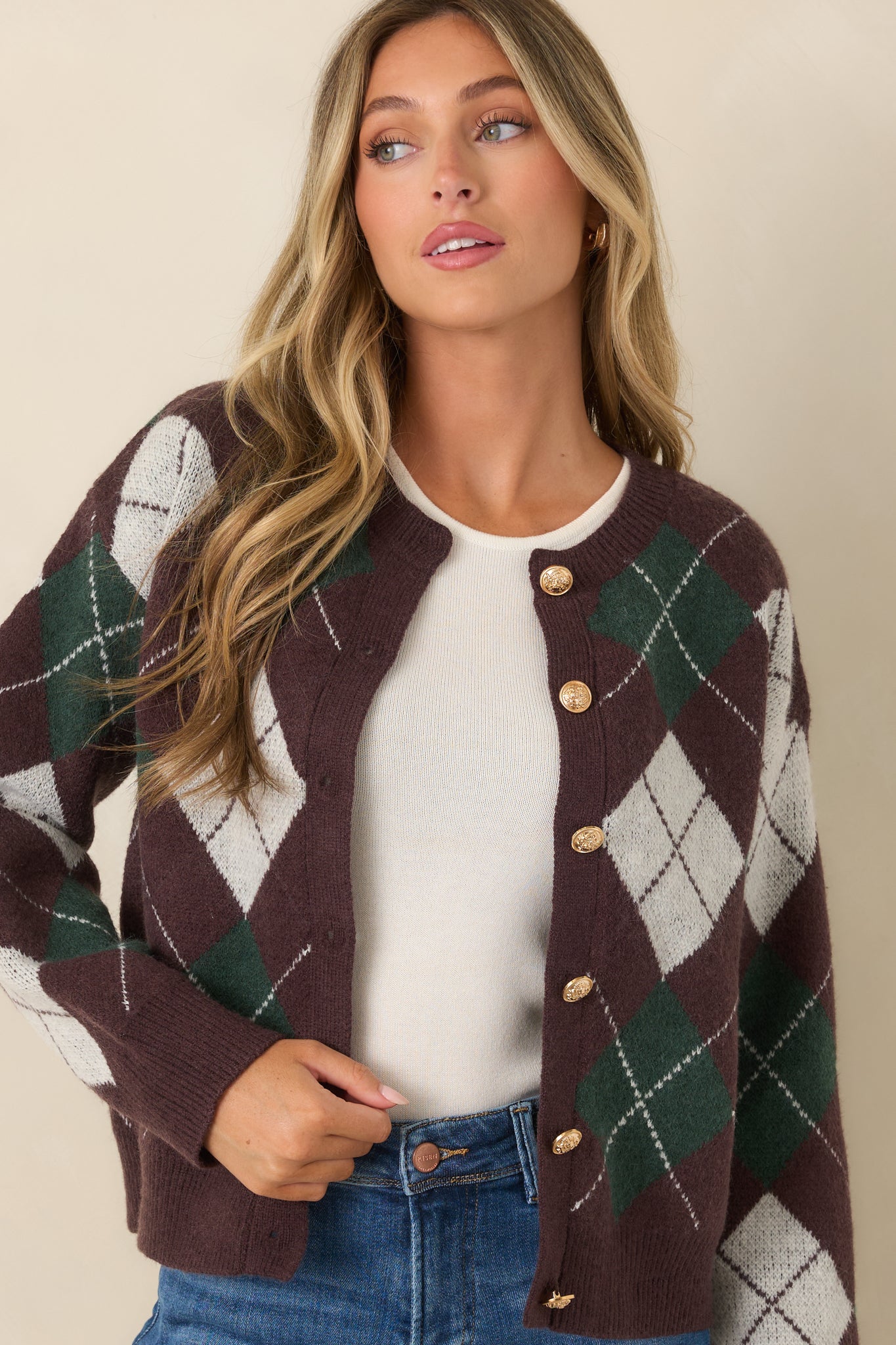 Argyle knit cardigan showcasing the ornate gold-tone buttons, soft texture, and structured ribbed neckline.
