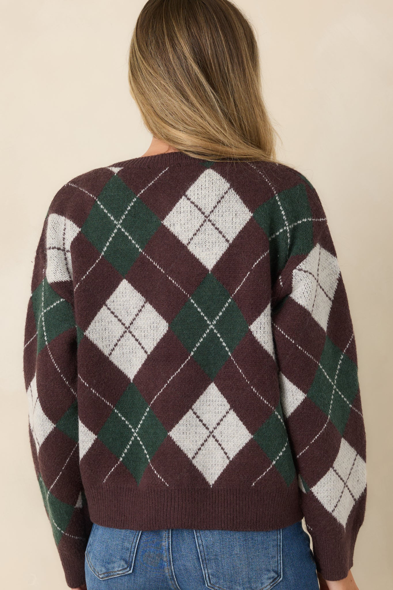 Rear view of the knit cardigan featuring a deep brown, hunter green, and ivory argyle pattern with ribbed trim and a relaxed silhouette.