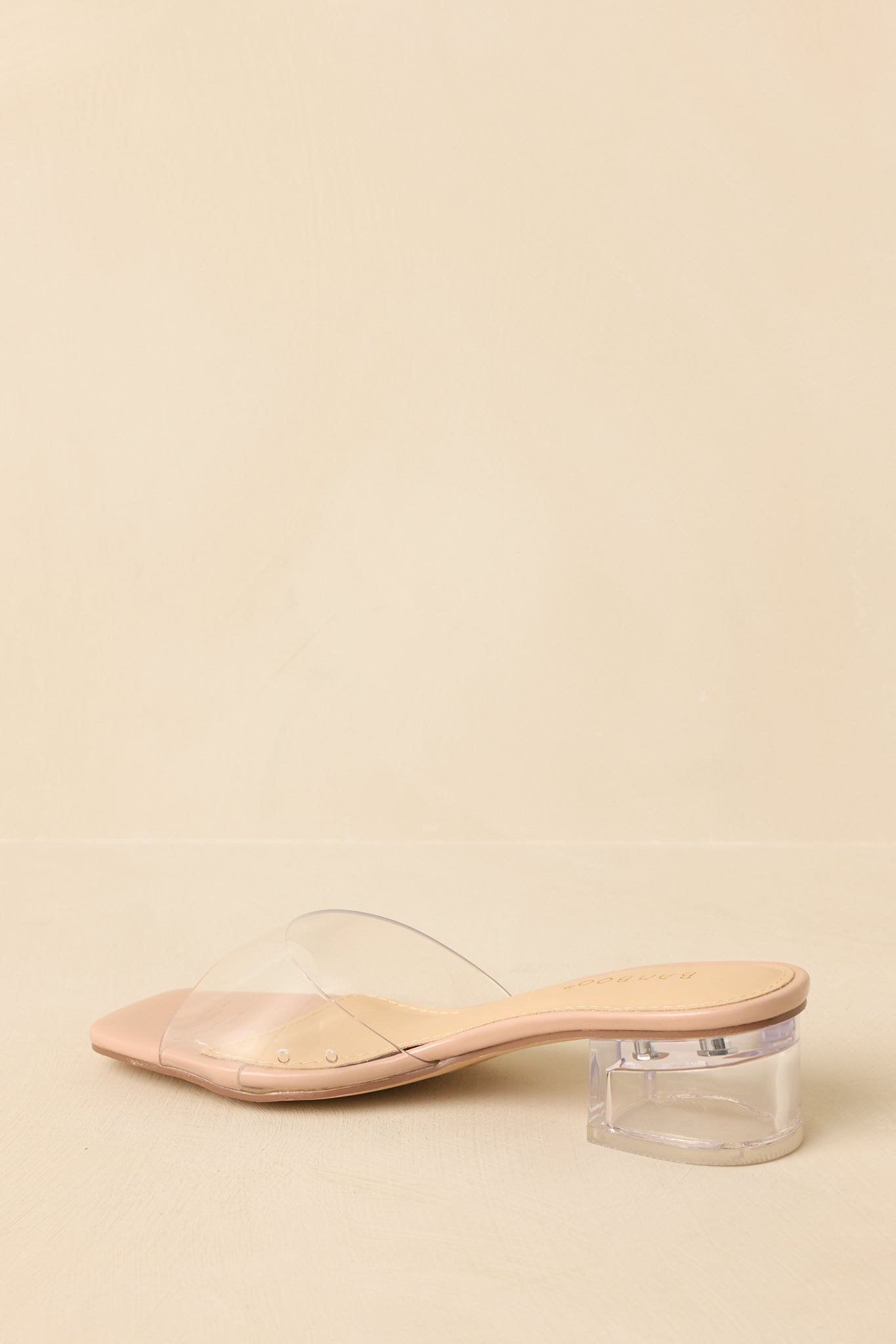 Back view of the beige low block heels highlighting the transparent block heel and open-back slide silhouette.