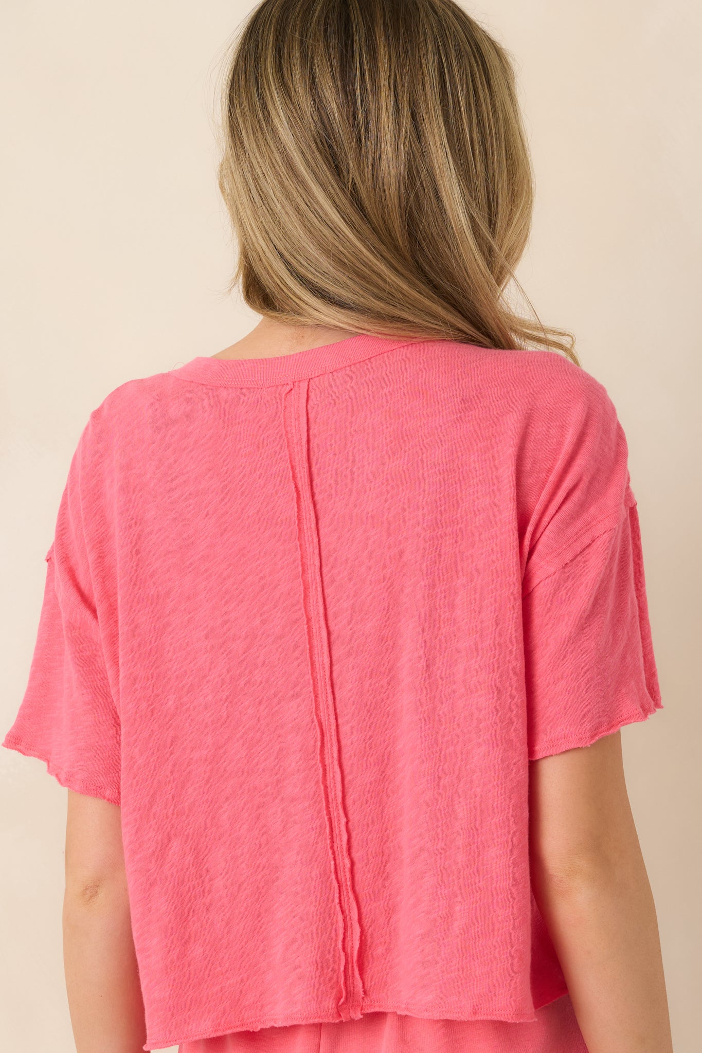 Back view of coral pink cotton tee displaying relaxed fit, short sleeves, and slightly cropped hem.