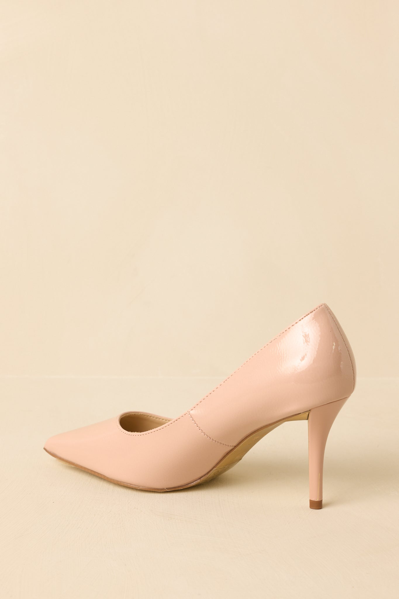 Back view of the nude patent heels highlighting the slim stiletto heel and streamlined slip-on construction.