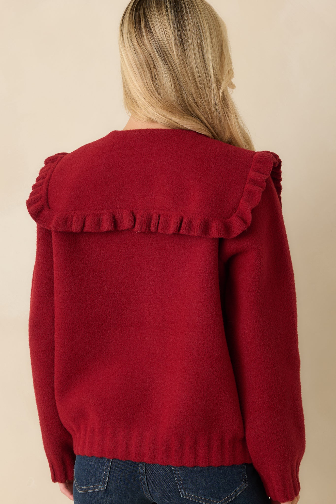 Back view of red knit cardigan showing smooth textured knit with ribbed hem and cuffs.