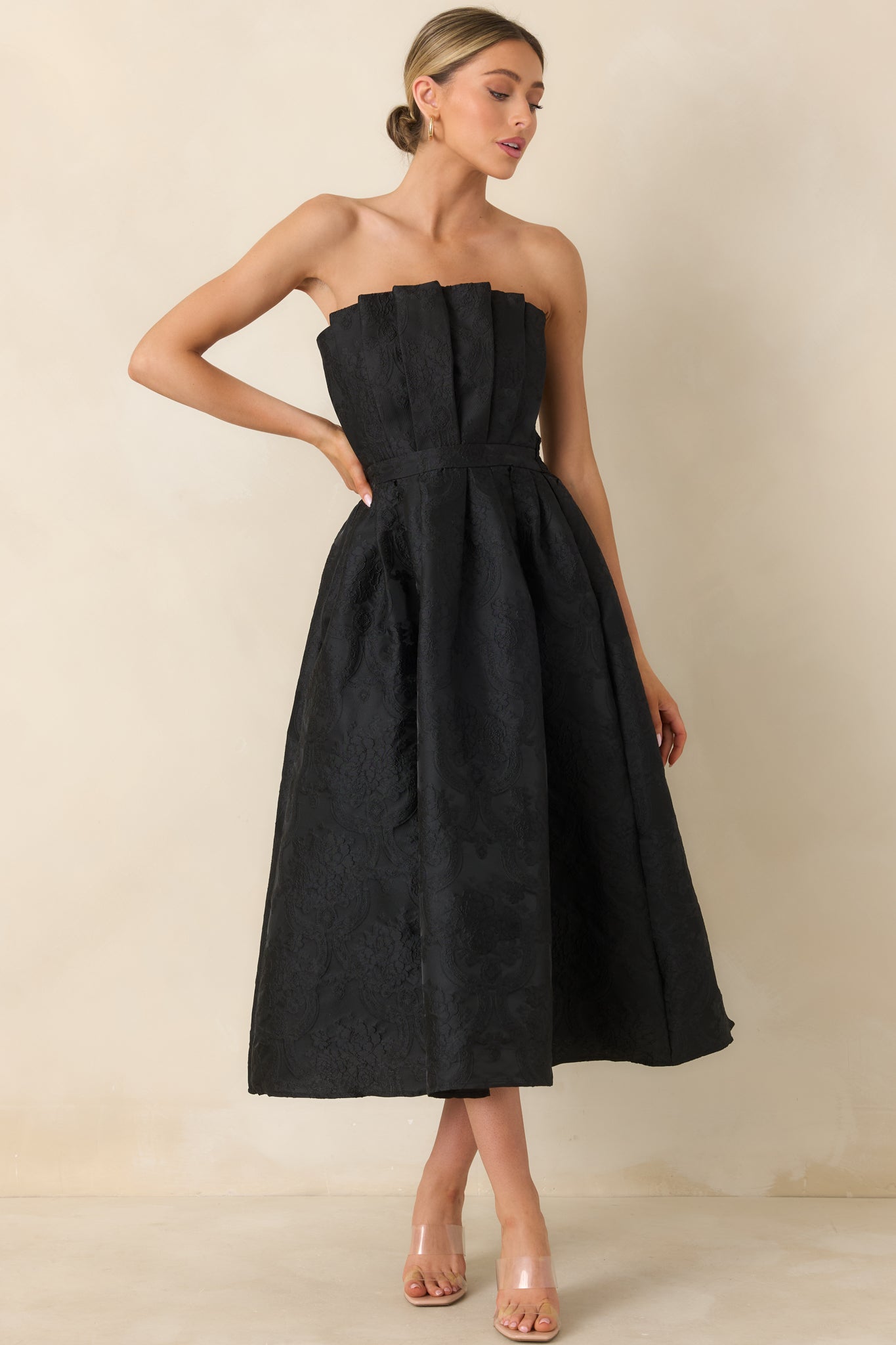 Front view of black strapless jacquard midi dress featuring a pleated bodice and softly pleated skirt.