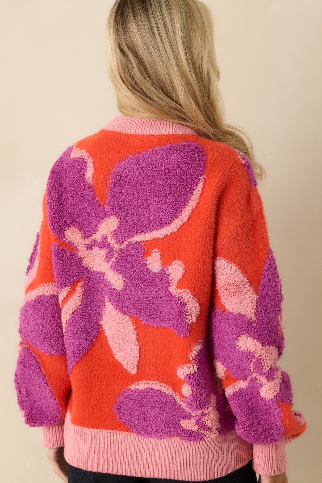 The back of the sweater shows the full floral pattern across the soft knit fabric with ribbed hem and cuffs.