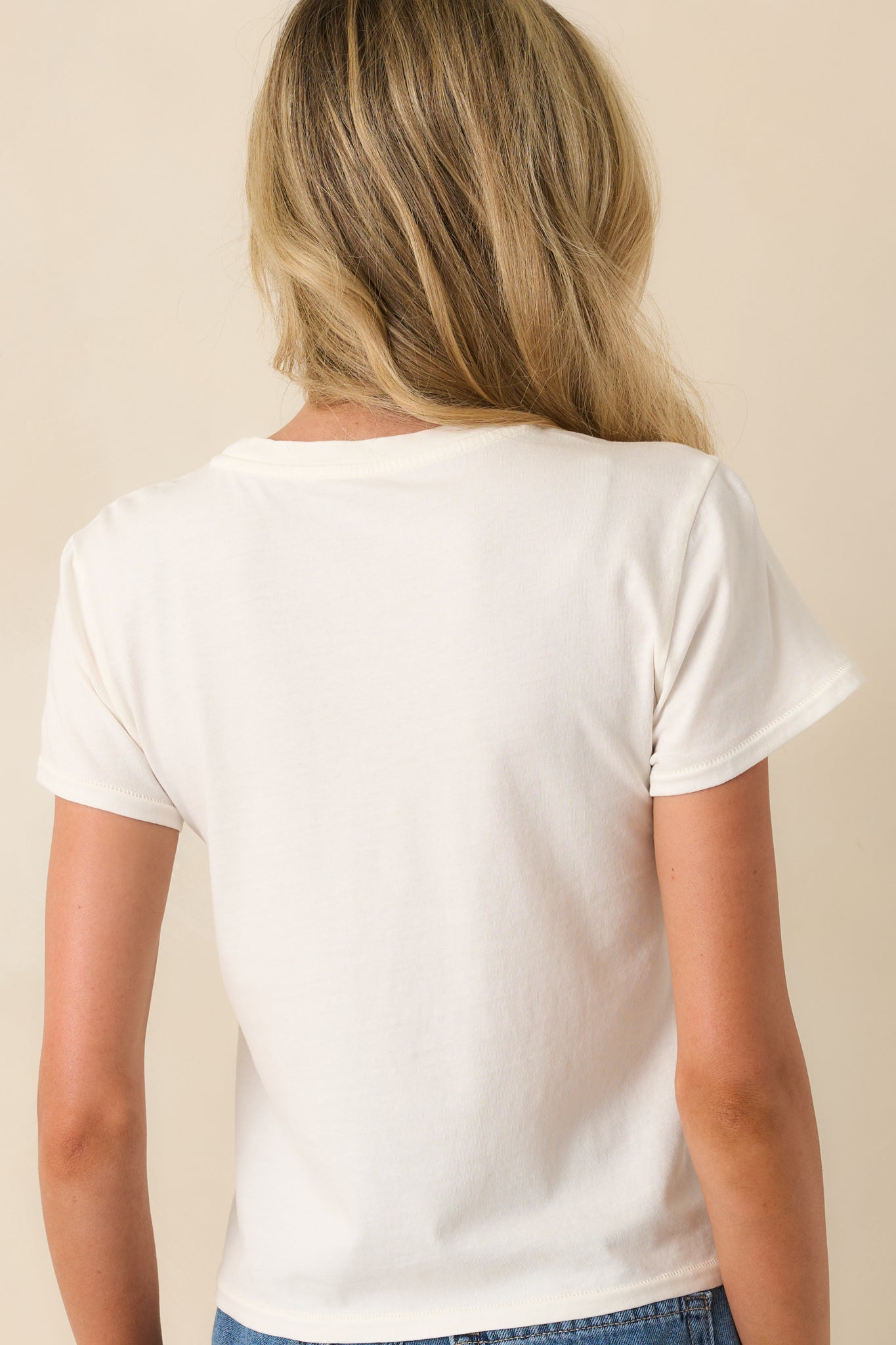 Back view of the top showing the clean ivory cotton jersey with no graphic and the relaxed drape of the fabric.
