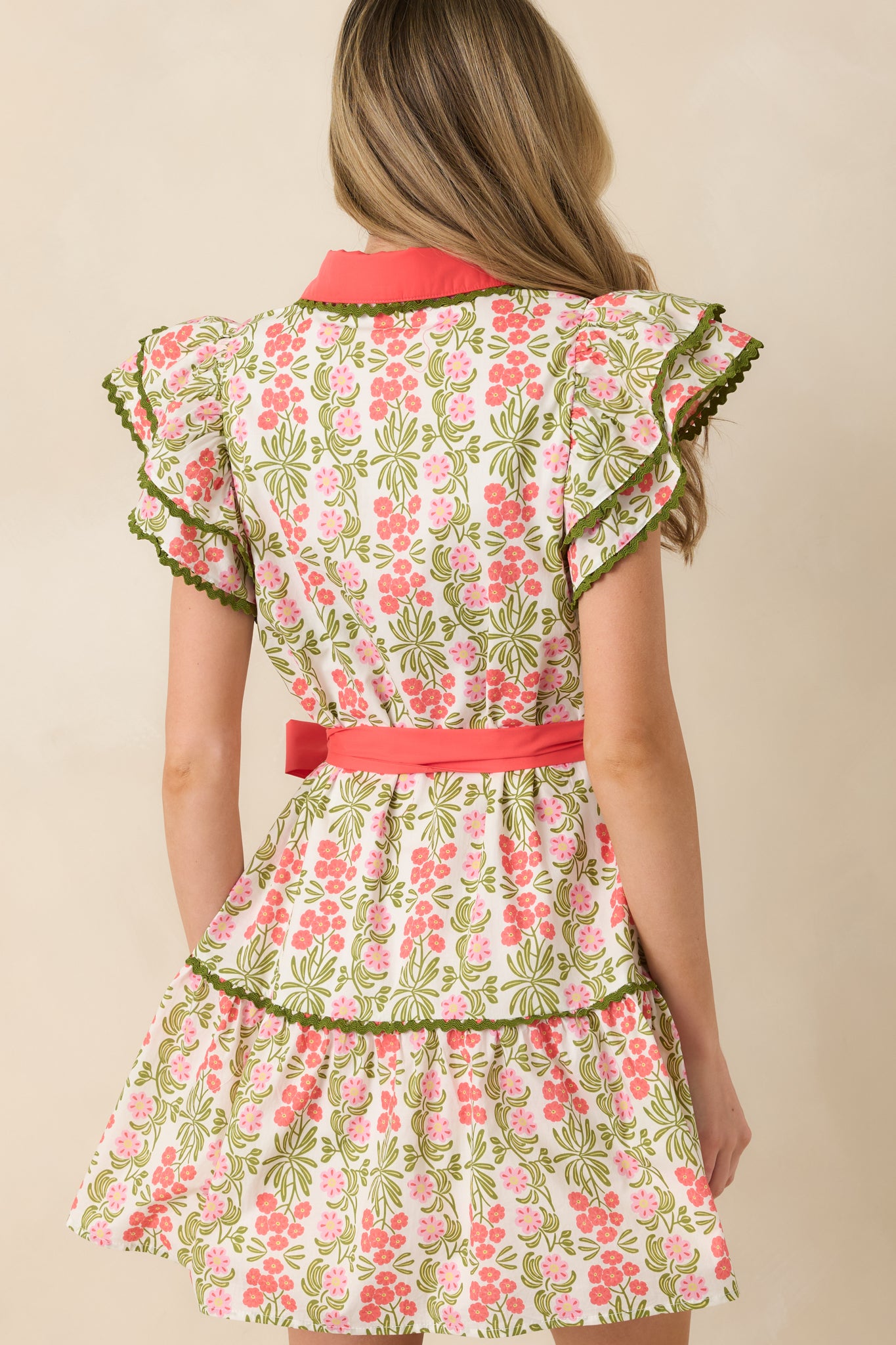 Back view of the coral pink mini dress displaying the tiered hem and continuous floral pattern.