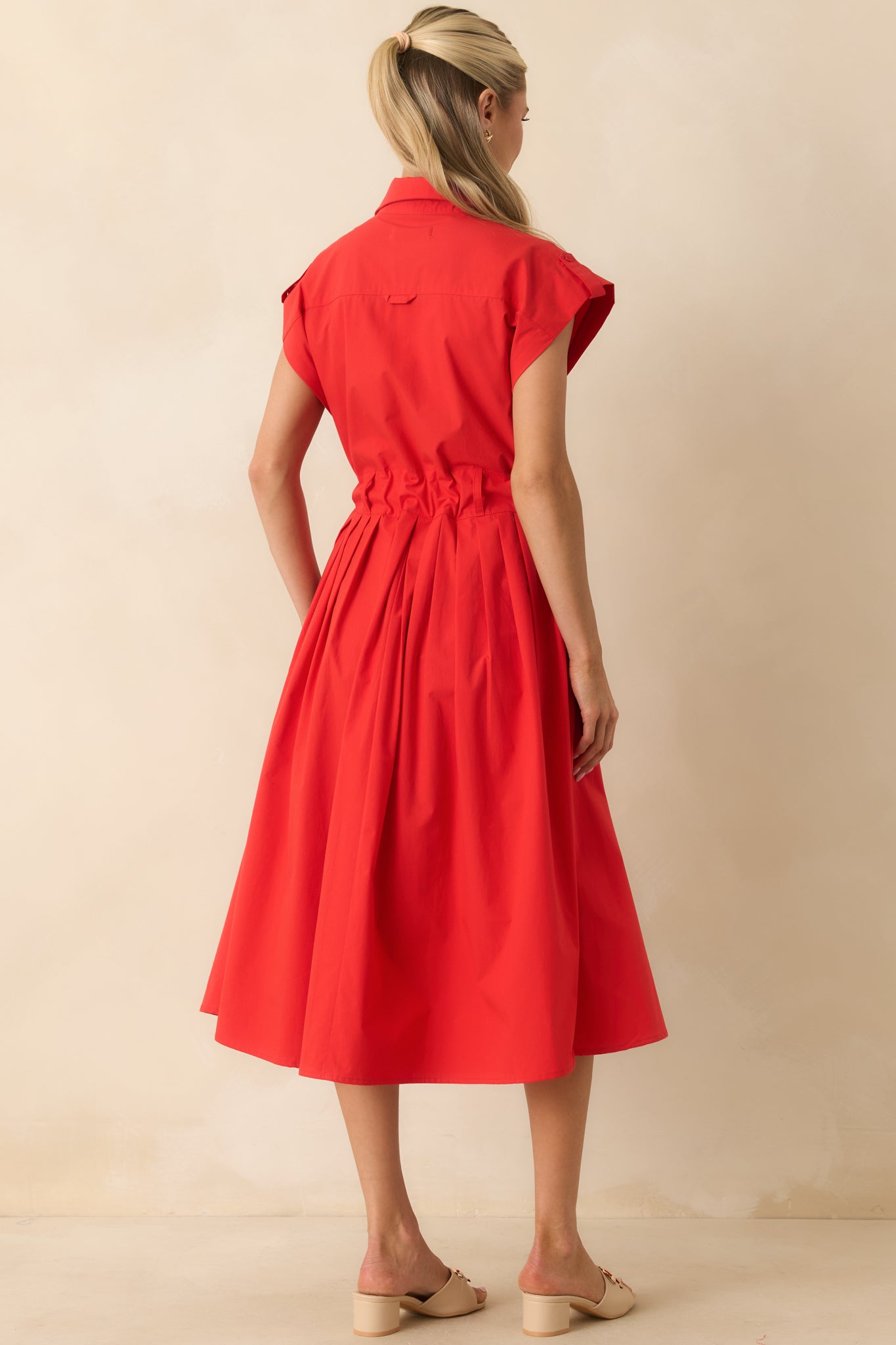 Back view of the midi dress featuring a cinched waist, cap sleeves, and flowing pleated skirt silhouette.