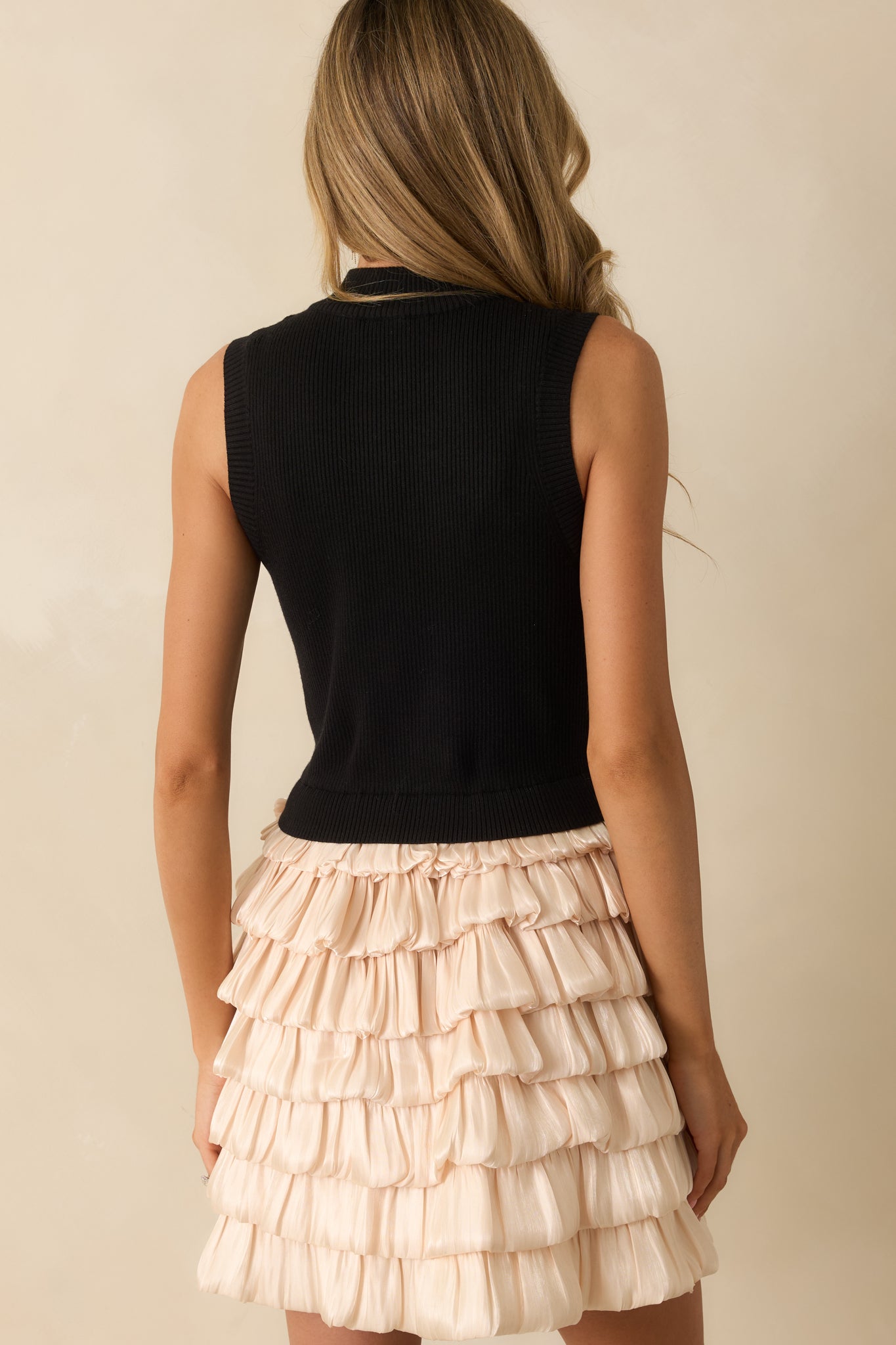 Rear view of the black and champagne mini dress with smooth knit back and tiered chiffon skirt.