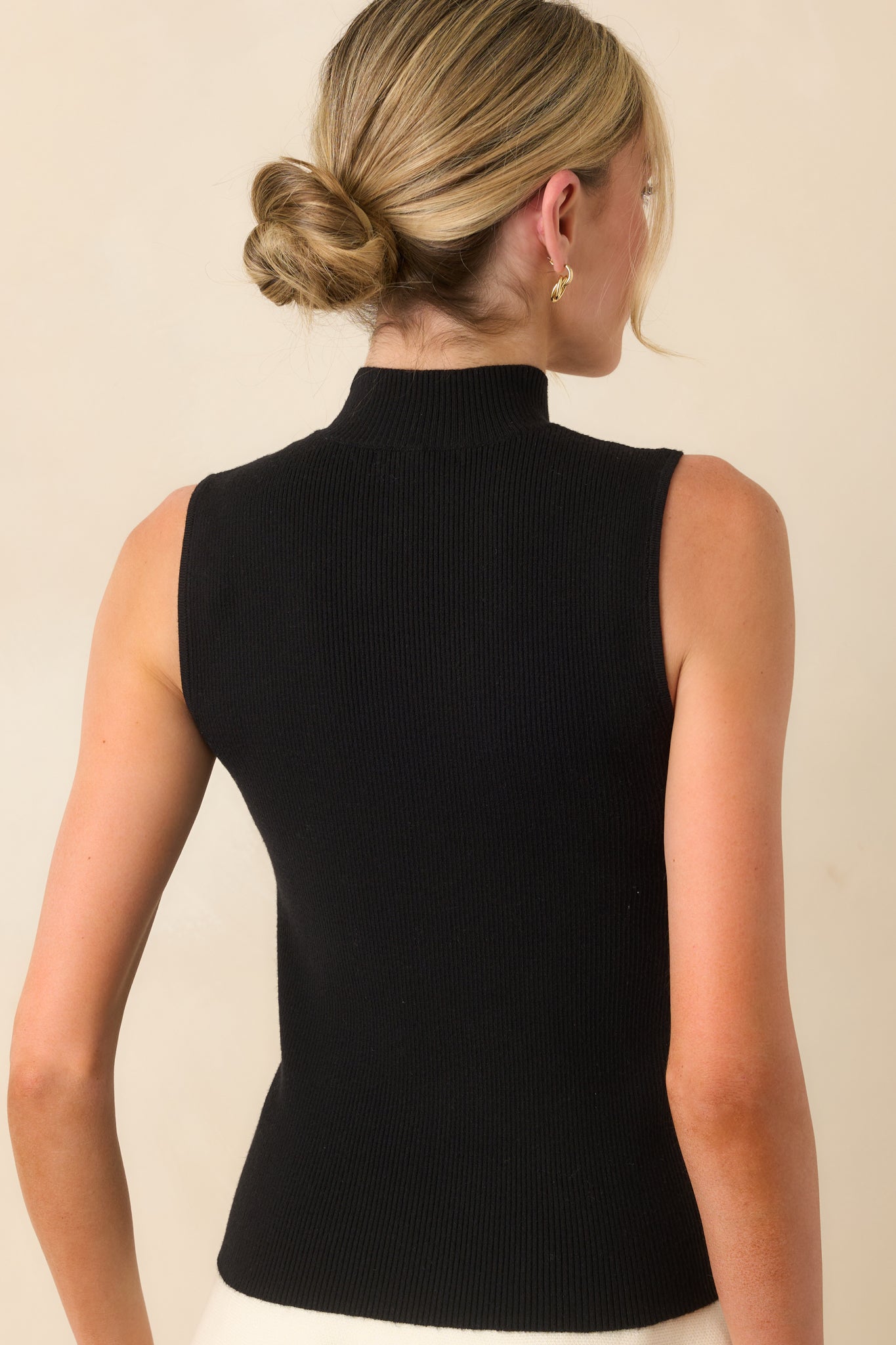 A back view of the black top displaying the fitted shape and sleeveless cut from behind.