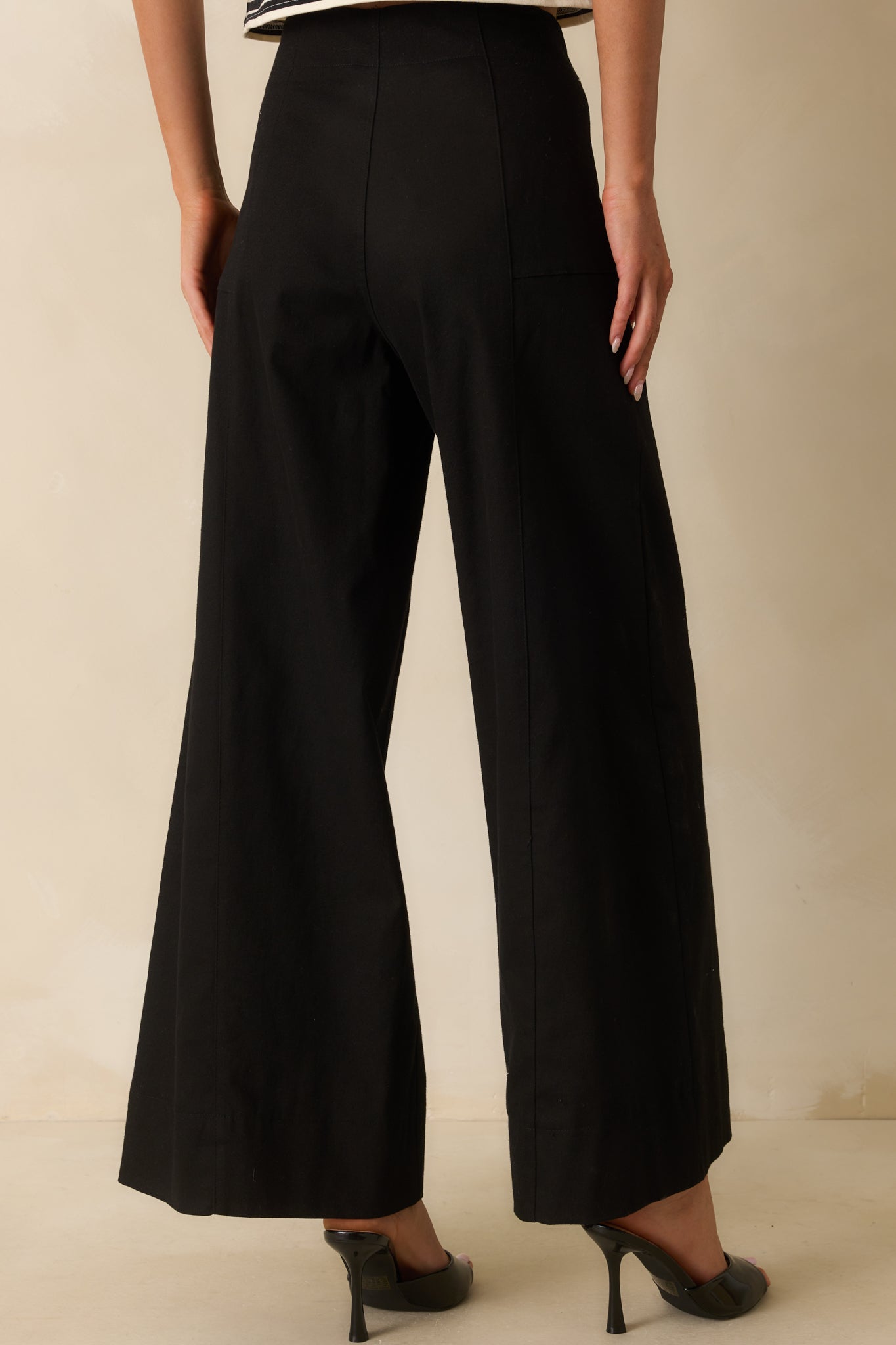 A back view of the black wide-leg pants showing the high waist and back pocket placement.