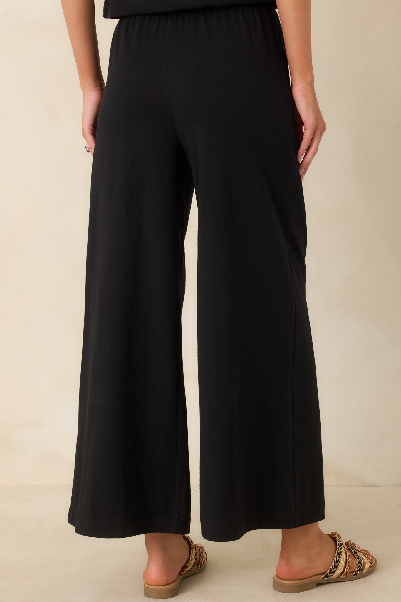Back view of black wide leg pants featuring a relaxed fit and smooth silhouette.