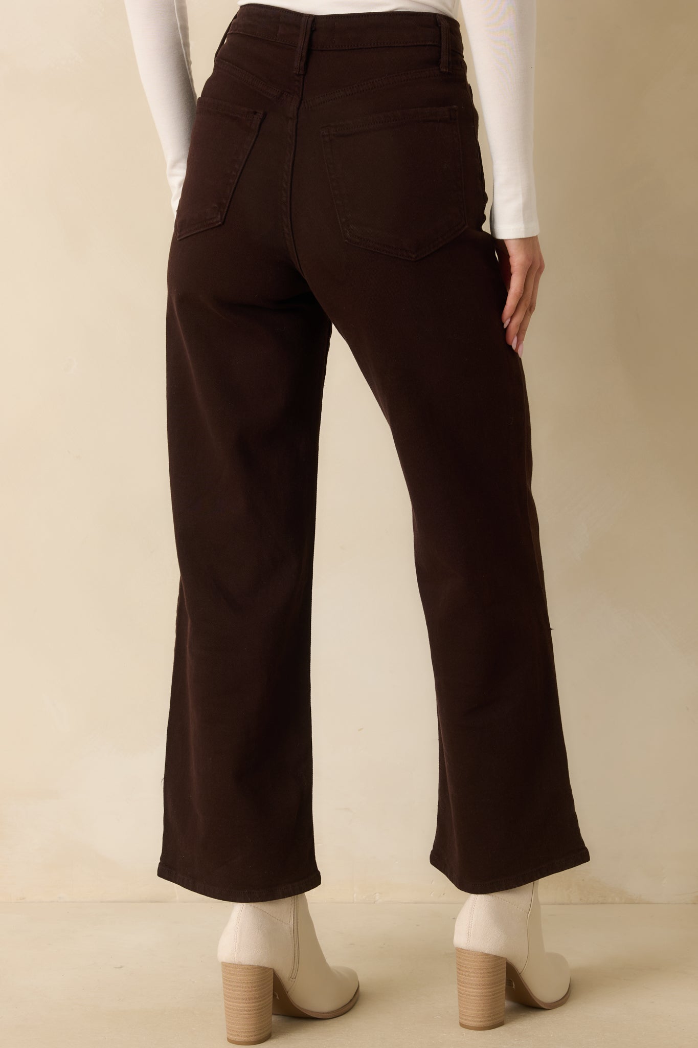 A back view of the dark brown jeans featuring functional back pockets, belt loops, and wide leg silhouette.