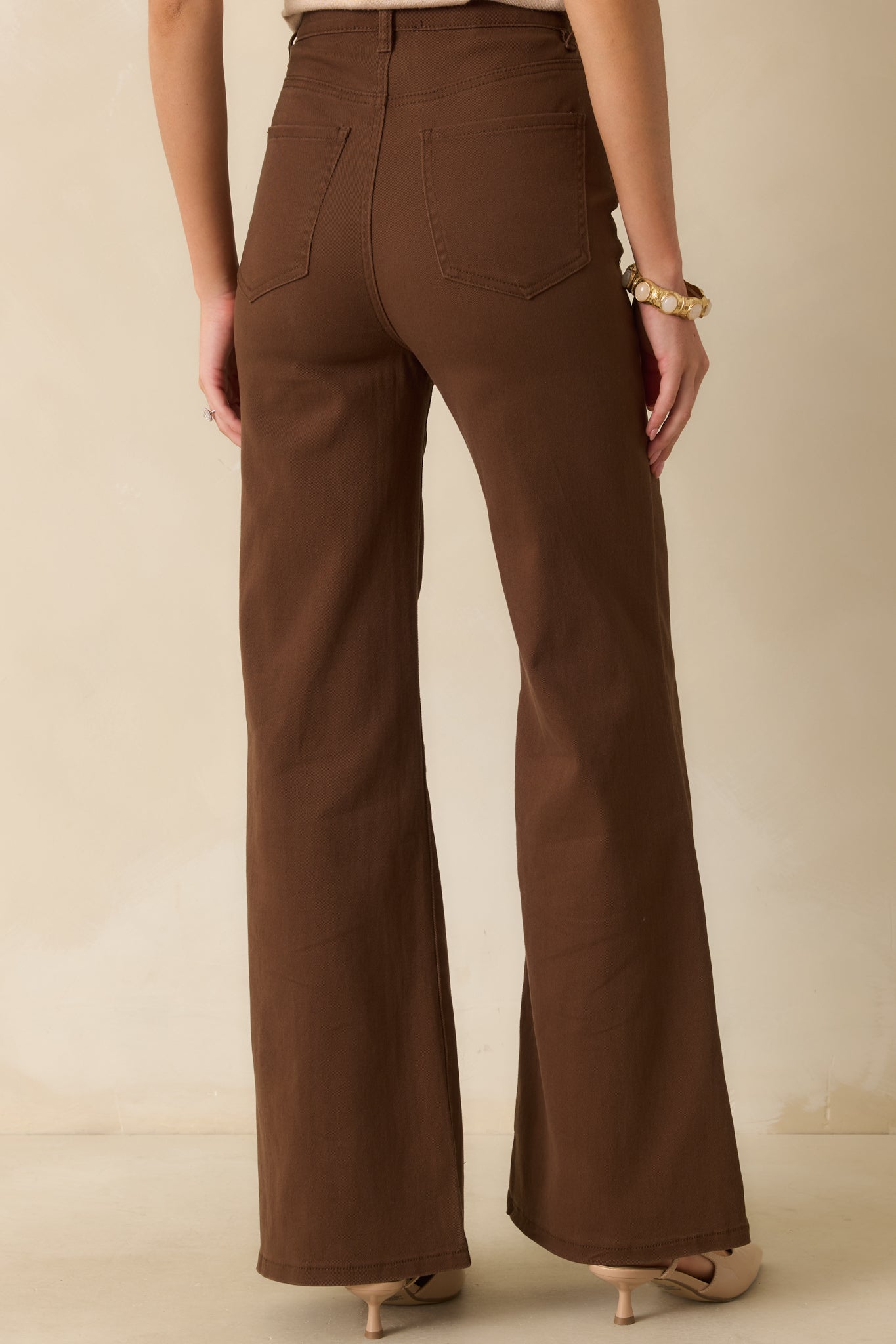 The back view of the brown jeans featuring a wide leg flare, high-rise waist, and functional back pockets.