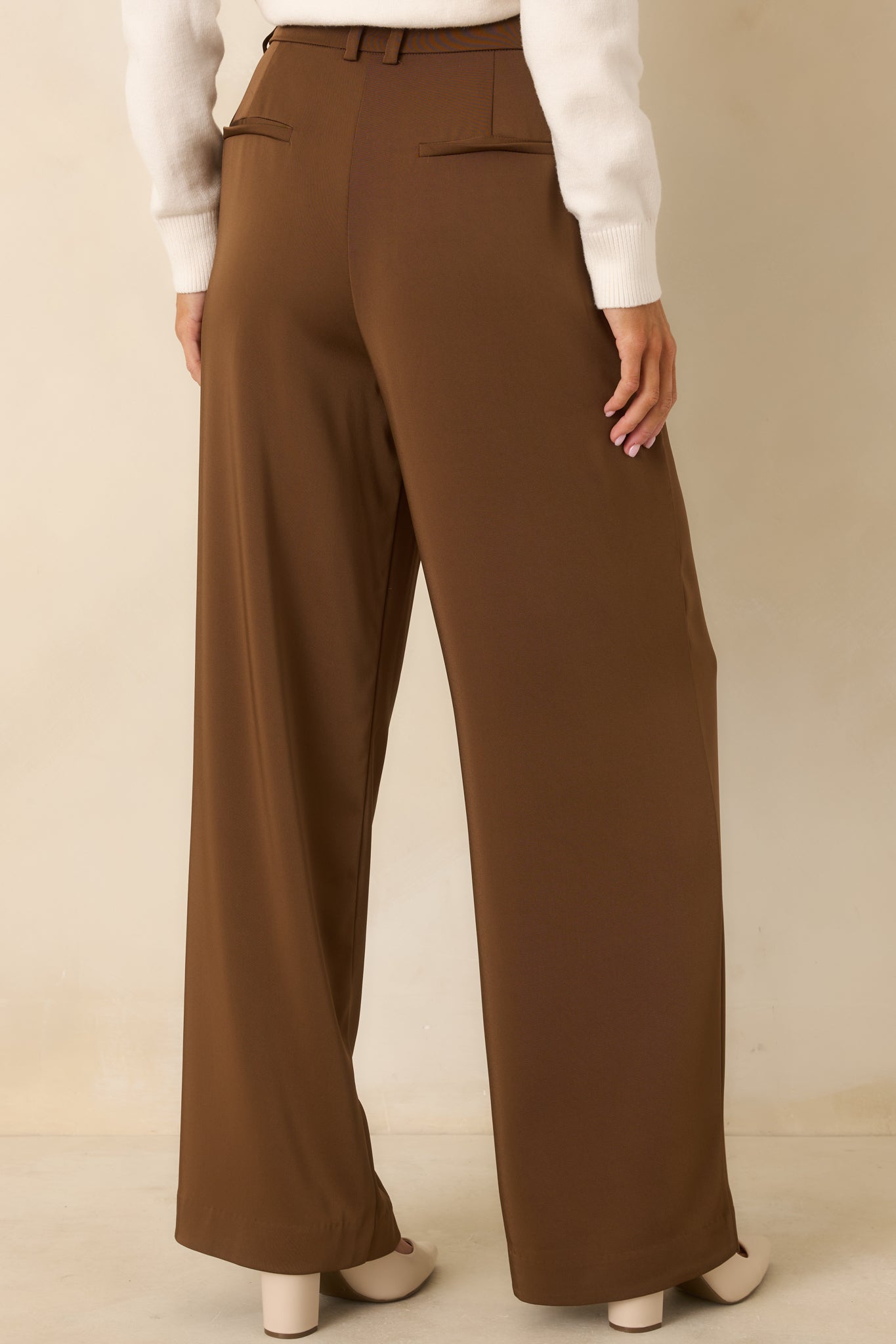 Back view of the brown trousers displaying faux welt back pockets and wide-leg silhouette.