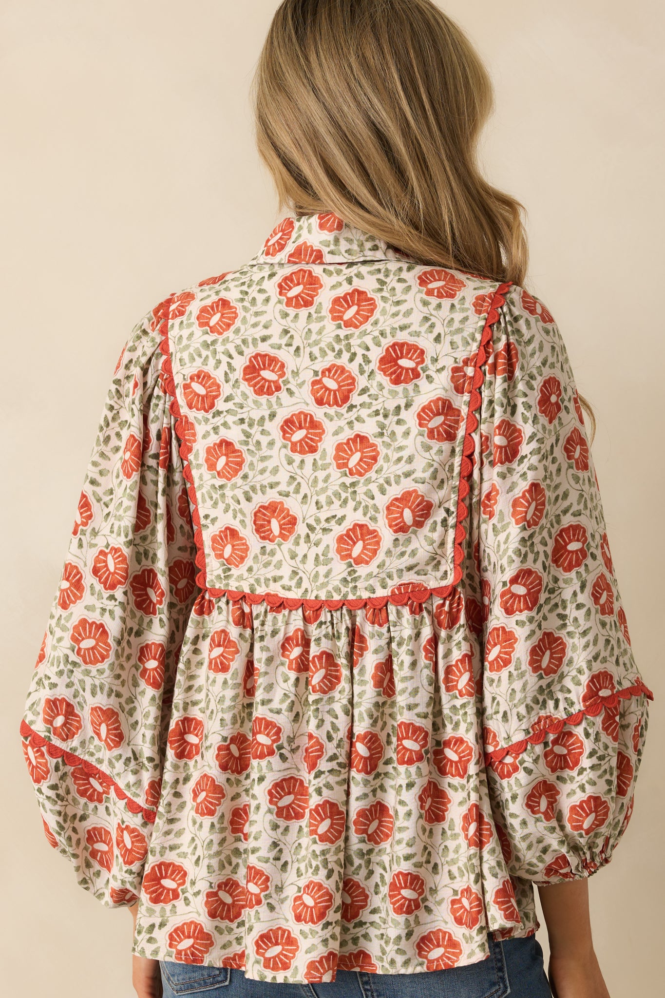 A back view of the burnt orange floral top showing the long sleeves and relaxed fit.