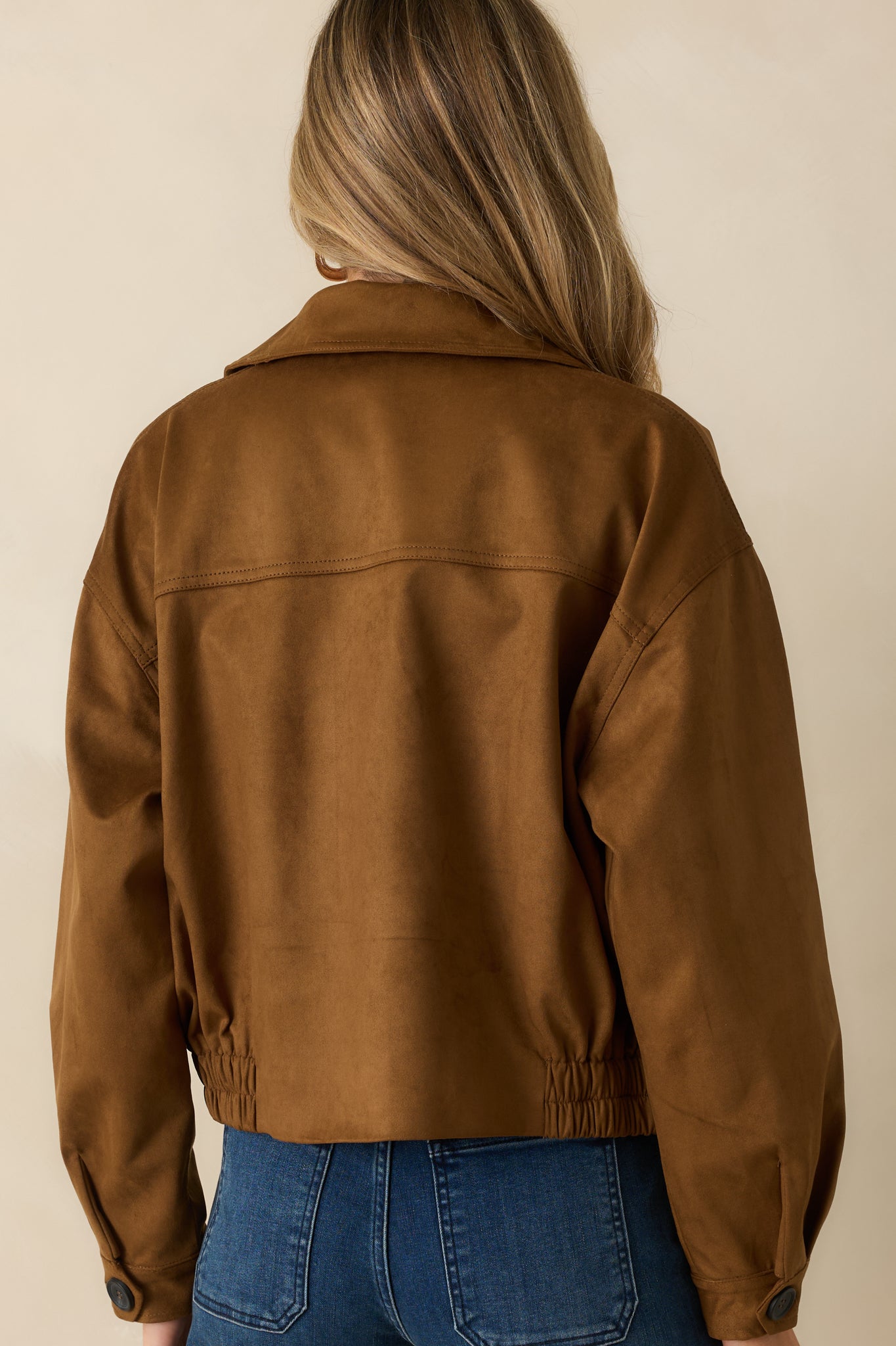 Back view of the camel cropped trench coat, showing the elasticized hem and clean back silhouette.