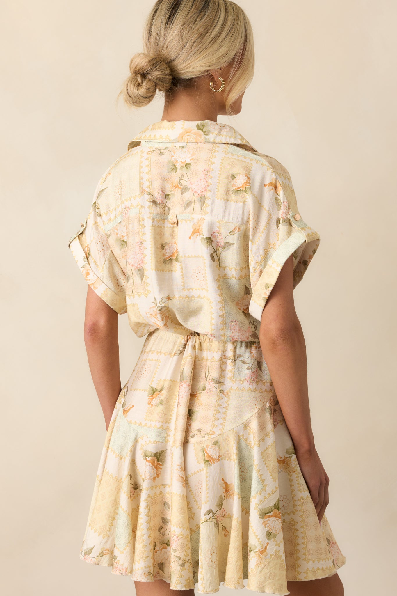 A back view of the yellow mini dress displaying the cinched waist from the drawstring tie and the flared skirt shape.