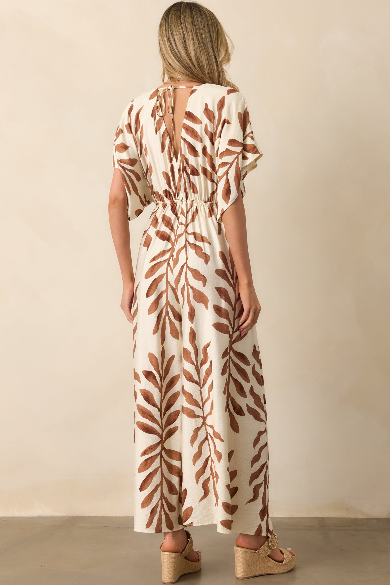 Back view of the jumpsuit displaying the v-back design with self-tie closure and continuation of the botanical print.