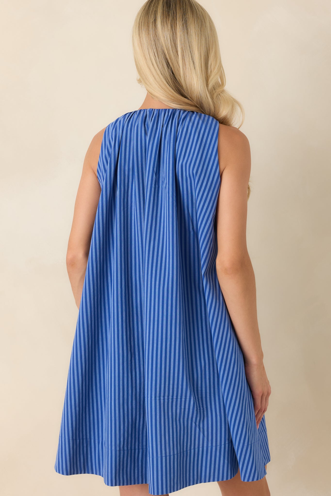 Back view of the electric blue striped mini dress showcasing the relaxed swing silhouette and clean sleeveless design.