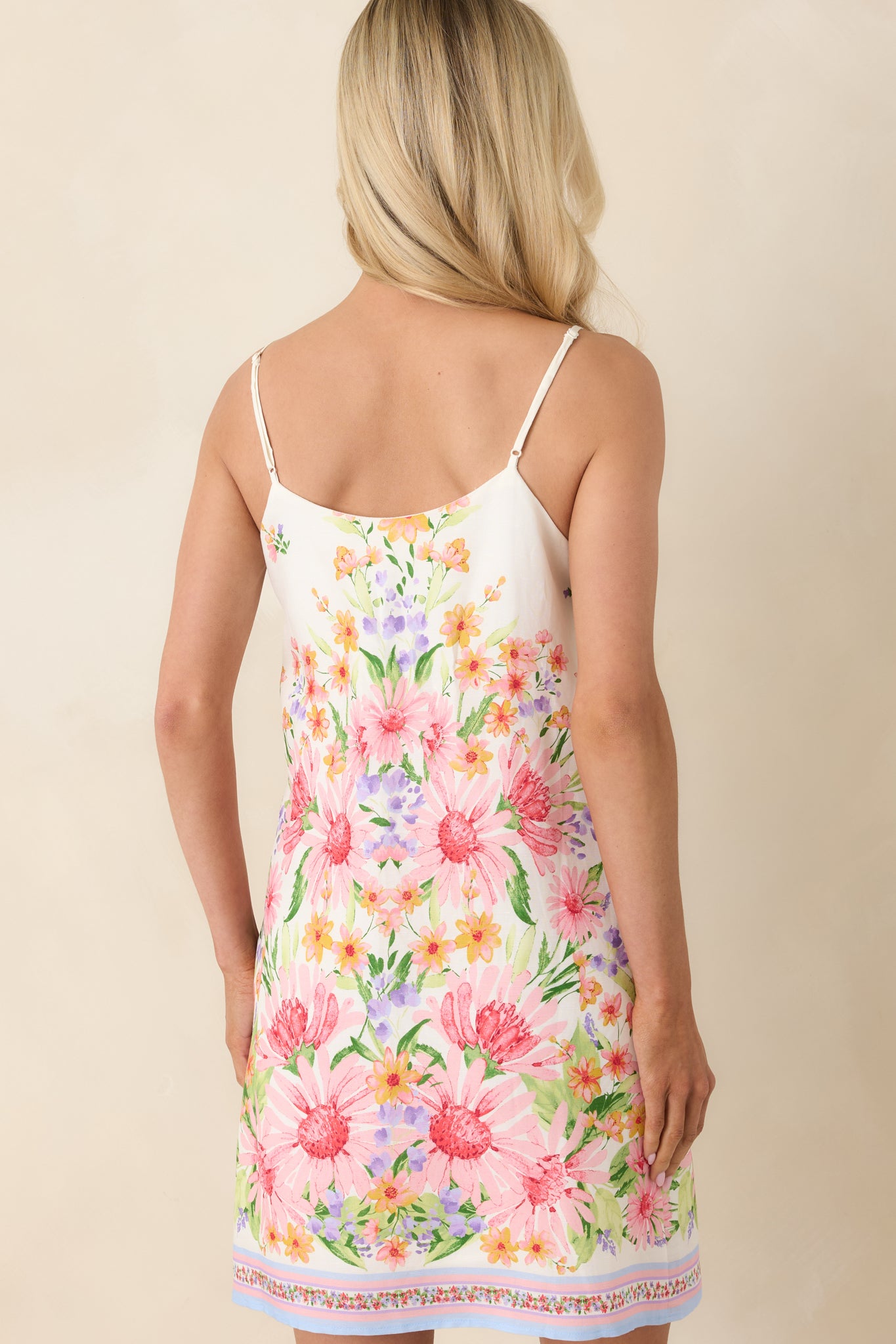 Back view of the mini dress featuring adjustable spaghetti straps, relaxed fit, and continuation of the floral print.