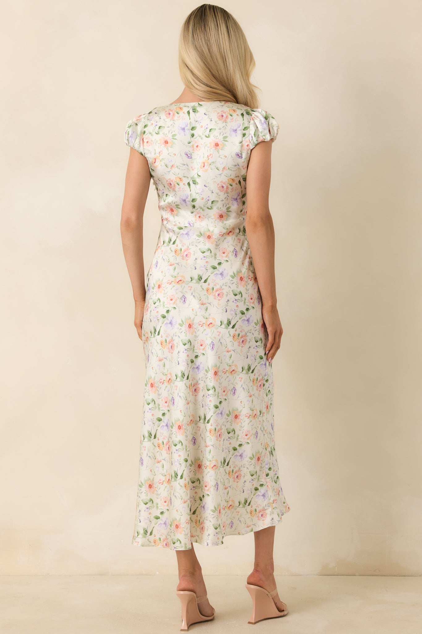 Back view of the floral midi dress featuring puff sleeves, a hidden side zipper closure, and a soft flowing satin-inspired finish.