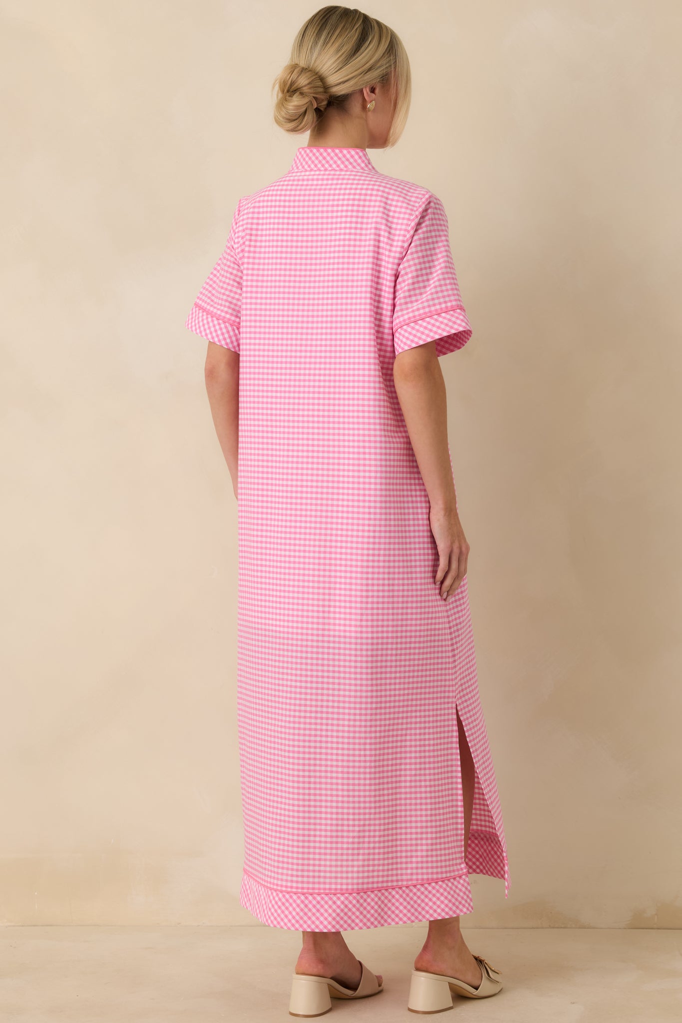 Back view of the pink gingham maxi dress featuring short sleeves, soft structure, and flowing maxi-length silhouette.