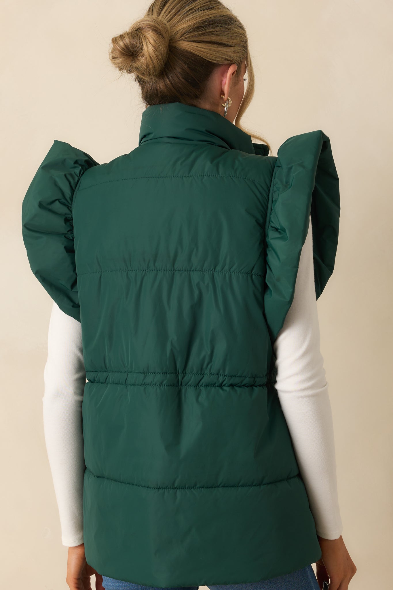 Rear view of the forest green puffer vest with horizontal puffer lines.