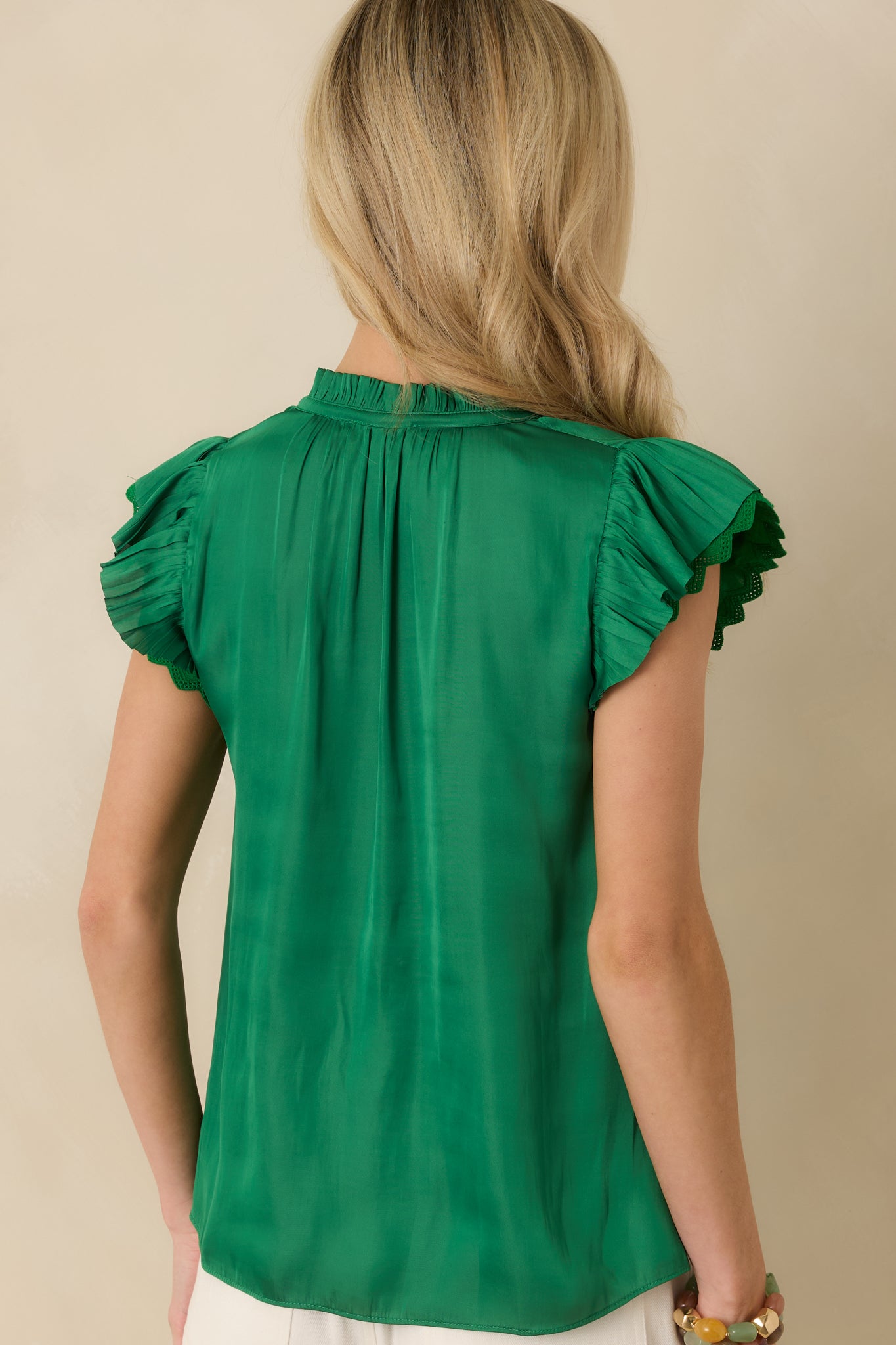 Back view of the green blouse highlighting the smooth woven fabric and relaxed back drape.