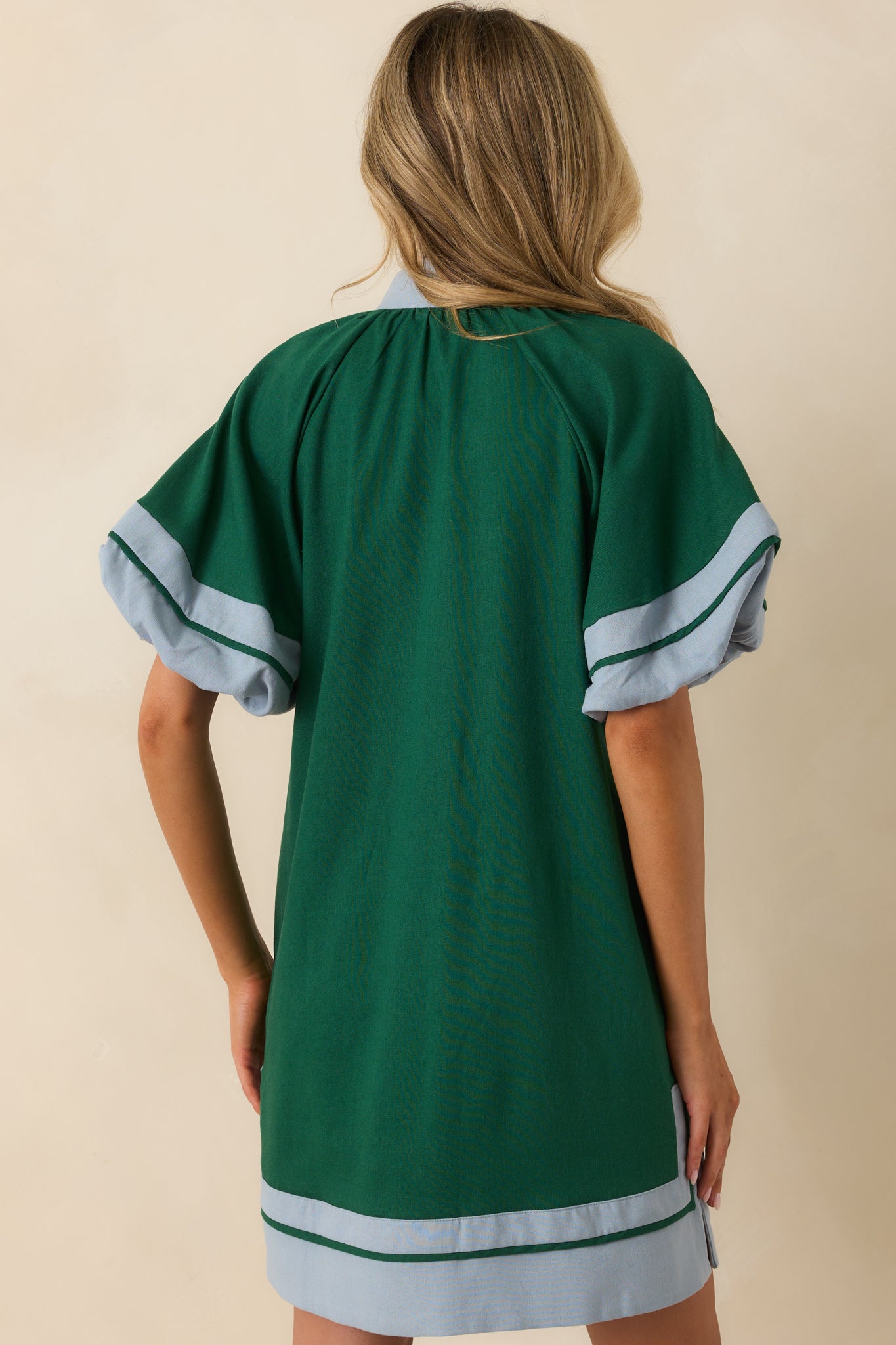 A back view of the green mini dress showing the shift silhouette and puff sleeves.