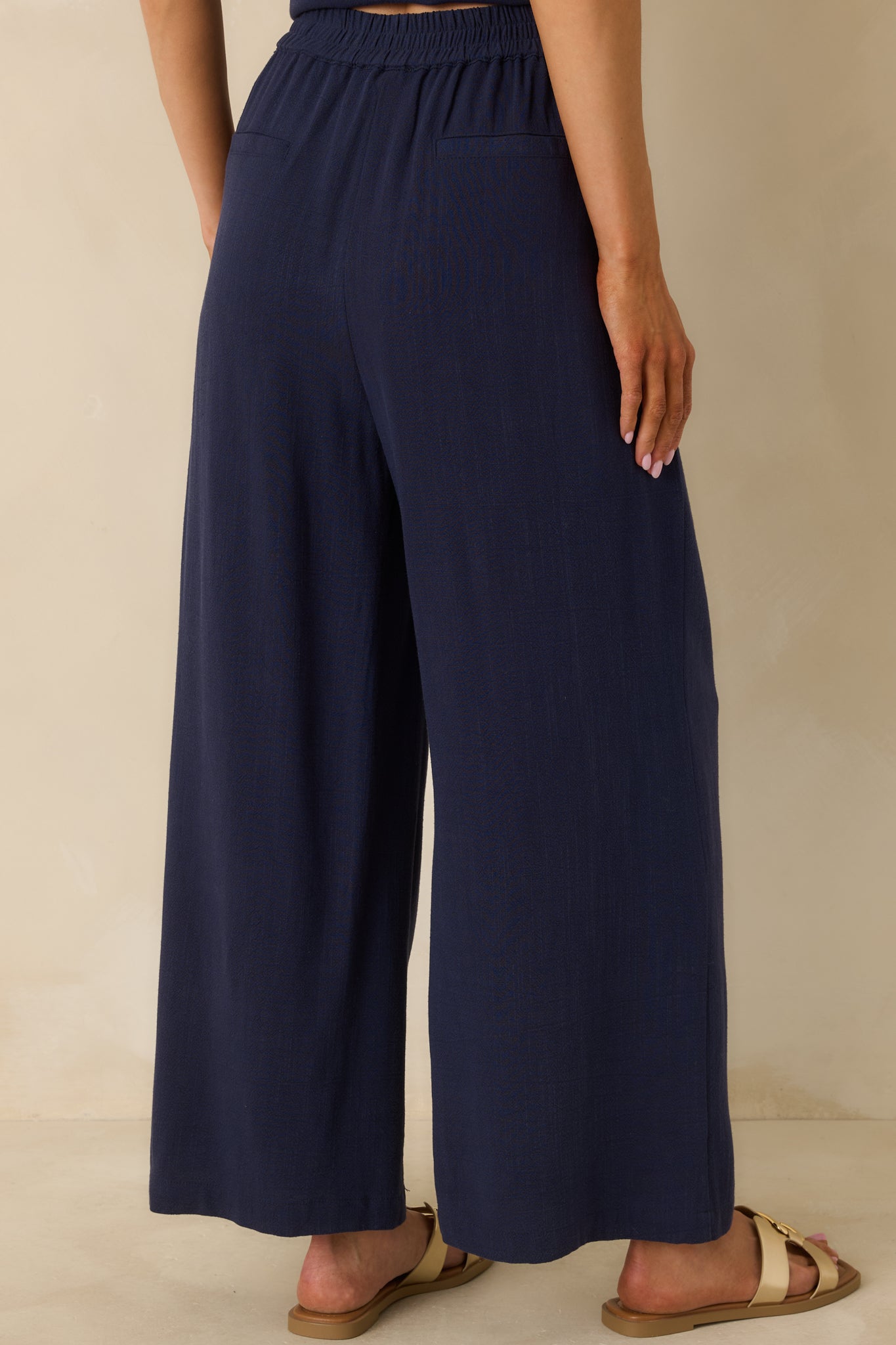 Back view of the navy wide leg pants highlighting the back patch pockets, relaxed fit, and full-length wide legs.