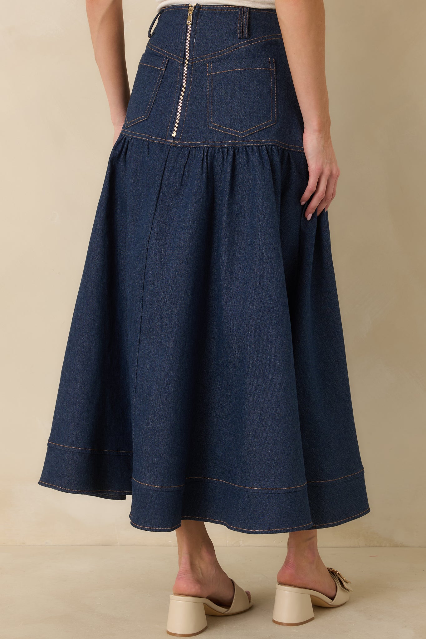 Back view of the denim maxi skirt highlighting the back zipper closure, pockets, and flared hem.