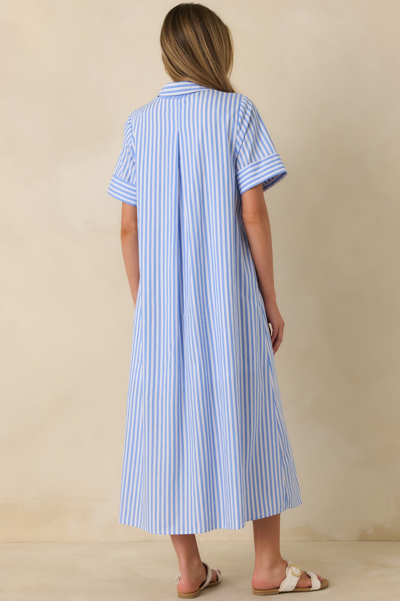 Back view of the blue and white striped shirt dress highlighting the center back pleat, relaxed A-line silhouette, and maxi-length hem.