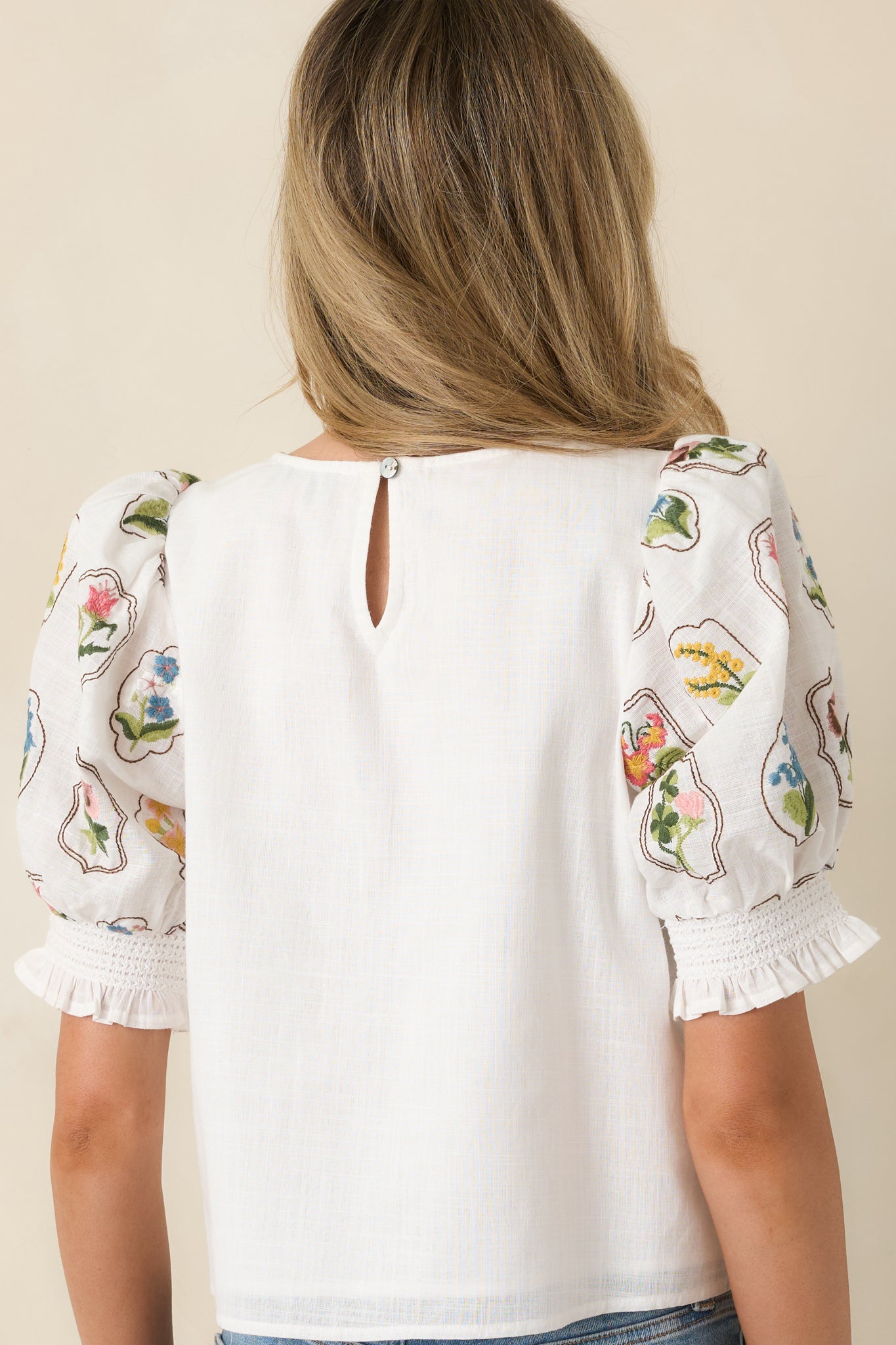 Back view of the embroidered ivory top highlighting the clean back design and puff sleeve shape.