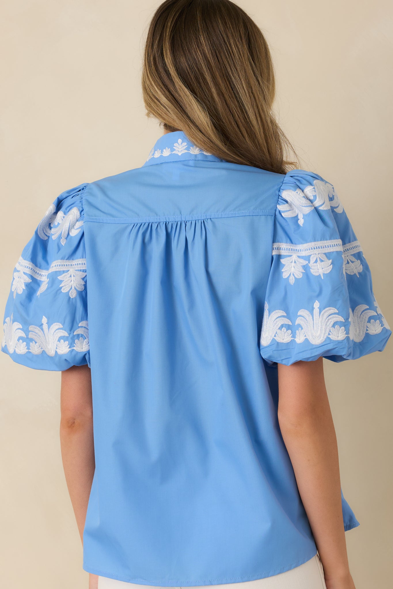 Back view of the blue top highlighting the smooth woven fabric, relaxed silhouette, and soft drape.