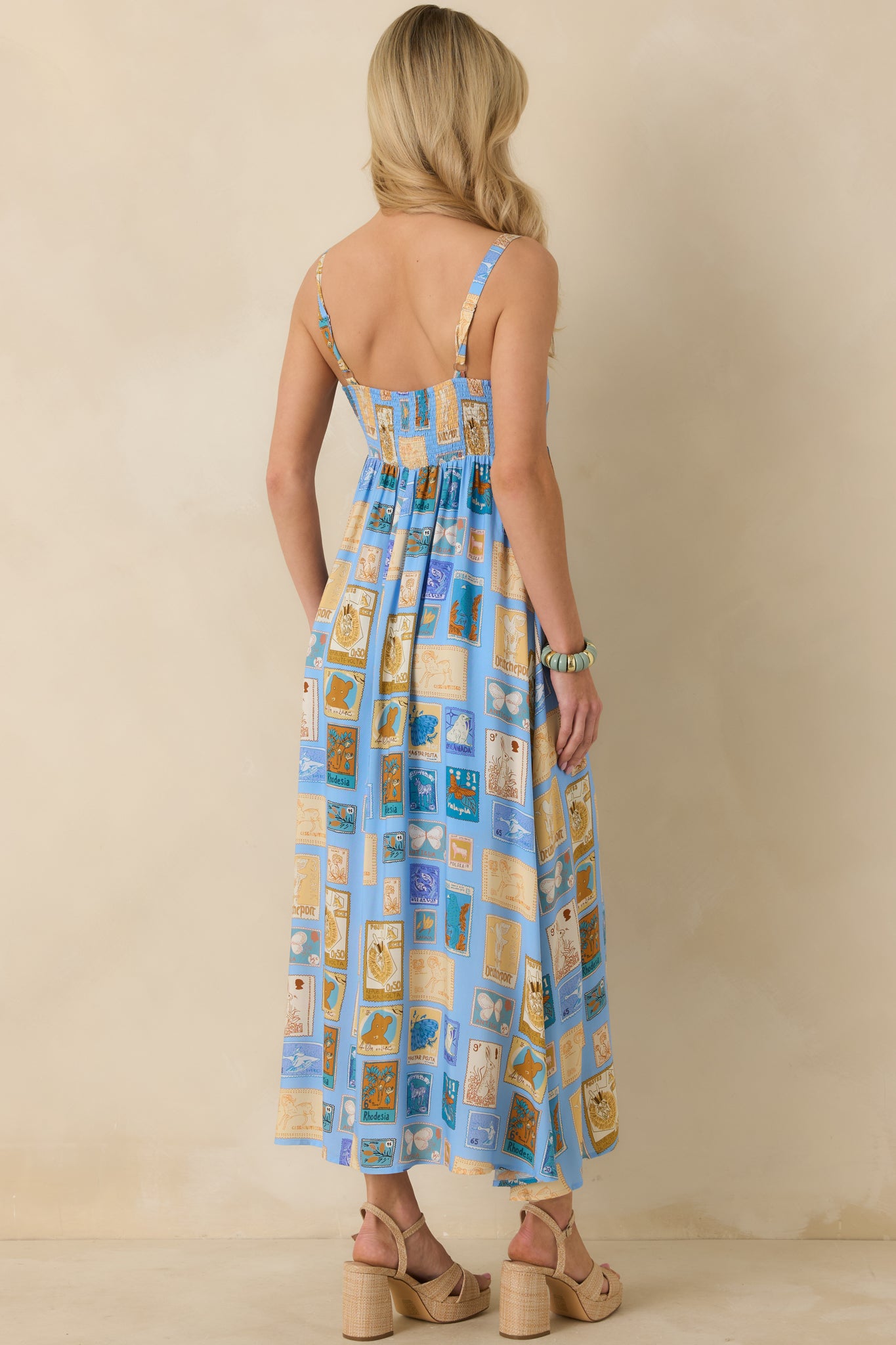 Back view of the blue multicolor midi dress highlighting the wide shoulder straps, fitted waist, and flowing skirt.