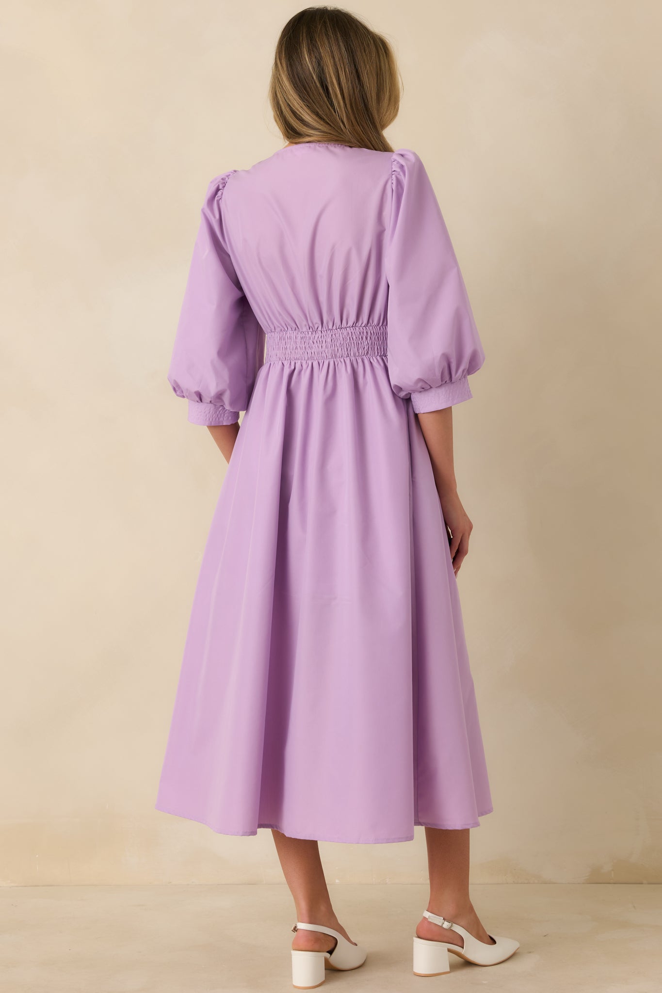 Back view of the lavender midi dress highlighting the smocked back panel and gently flared skirt shape.