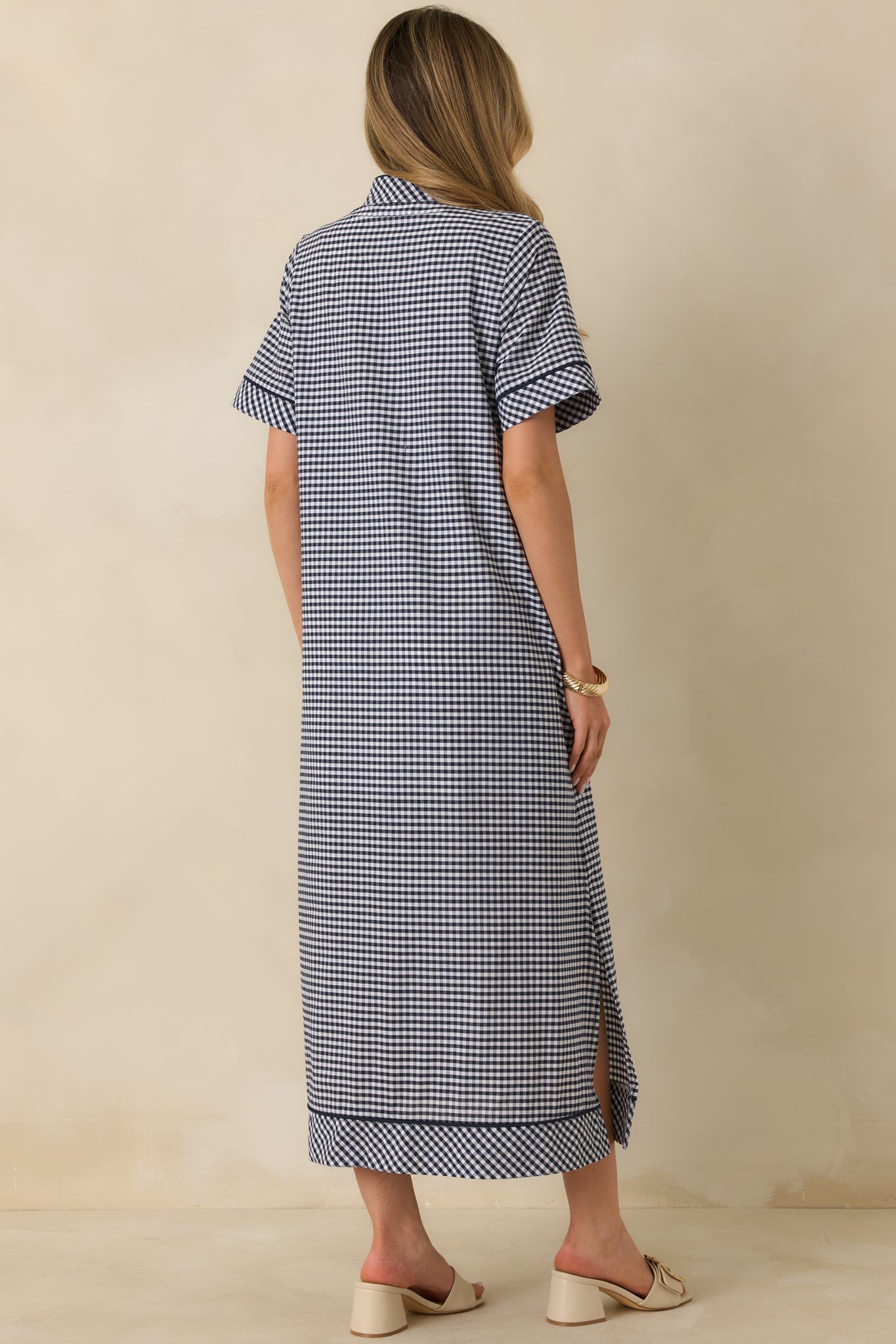 Back view of the navy gingham maxi dress highlighting the smooth drape, relaxed fit, and full-length silhouette.