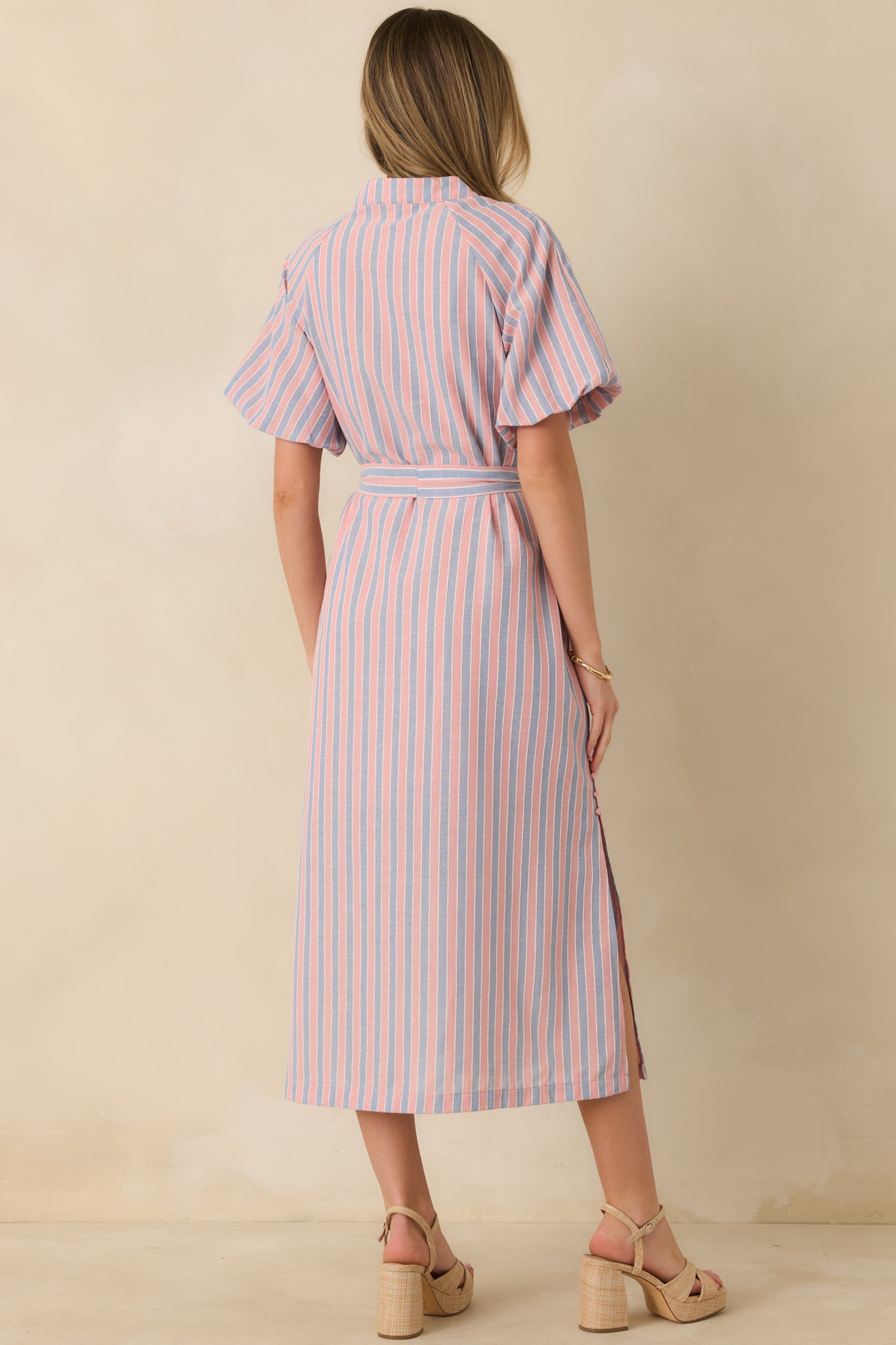 Back view of the pink and blue striped midi dress highlighting the straight midi-length skirt, smooth fabric, and softly structured shape.