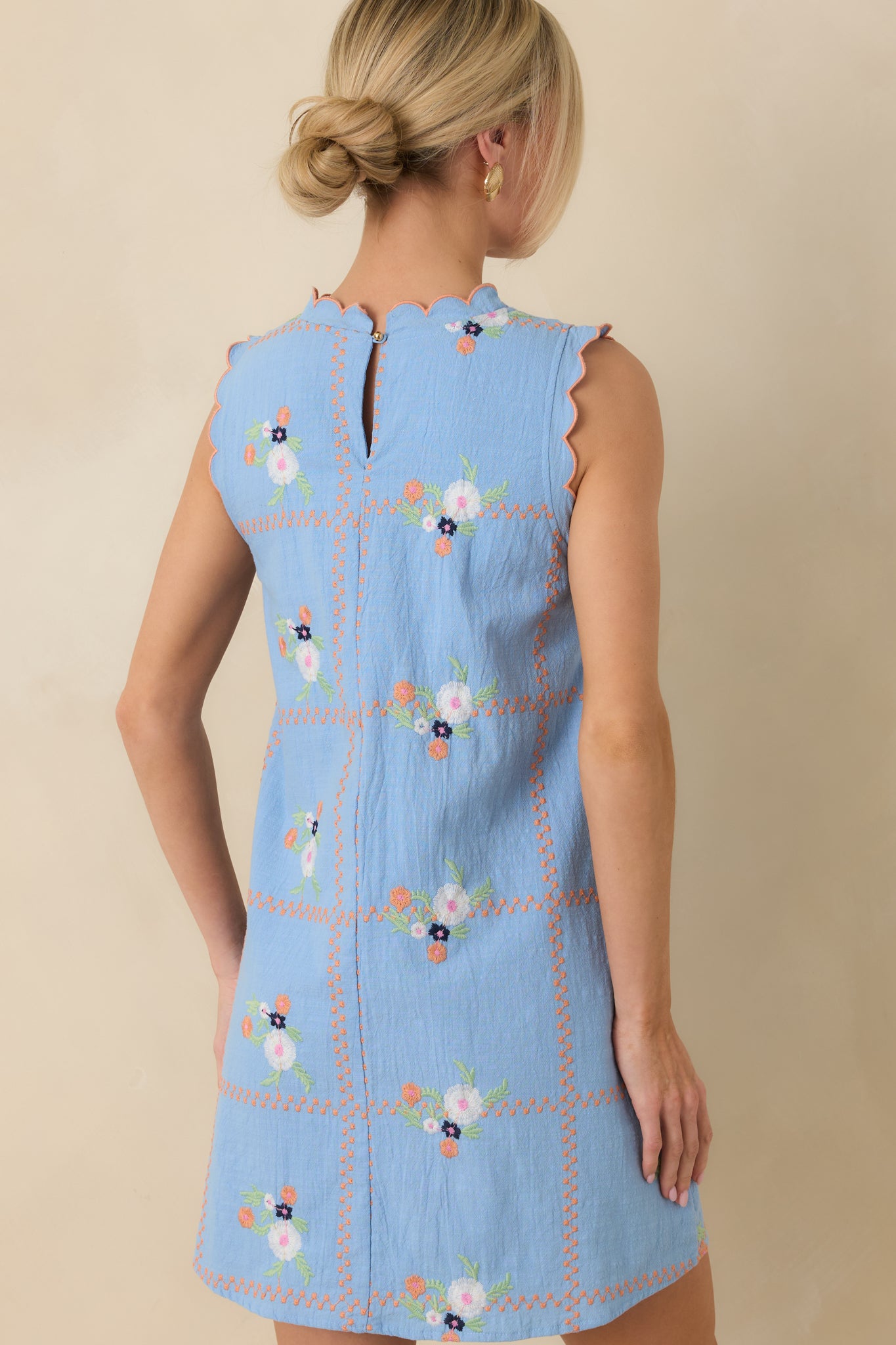 Back view of the light blue mini dress highlighting the subtle keyhole closure with button and relaxed straight fit.