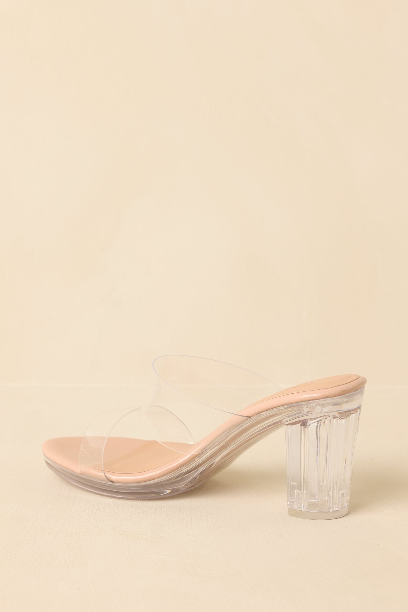 Back view of the beige platform block heels highlighting the transparent heel, platform sole, and open-back slide silhouette.
