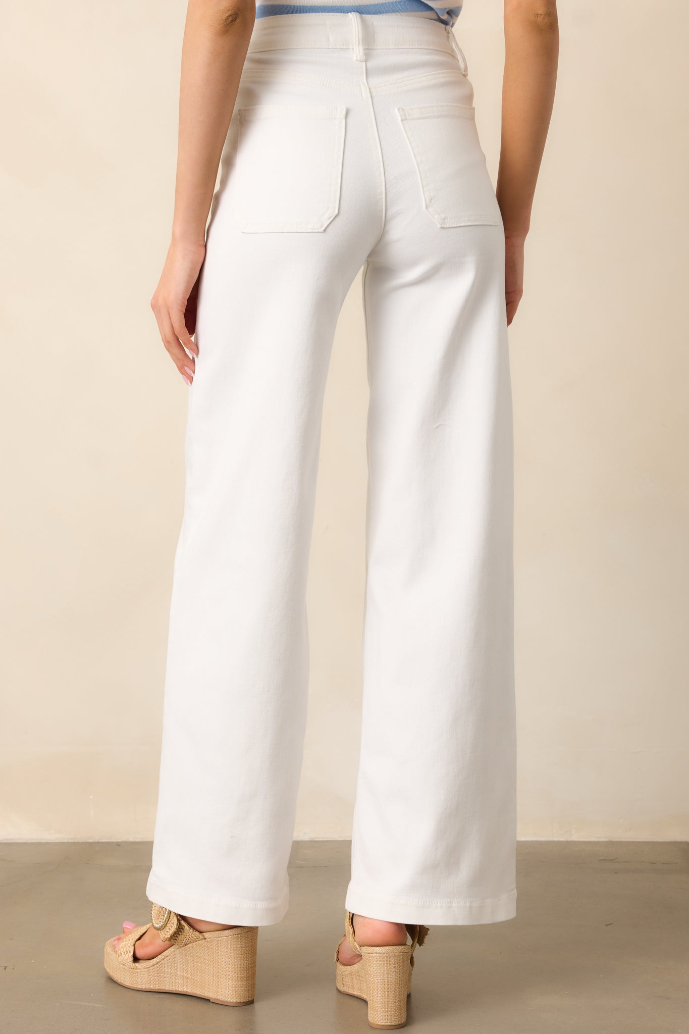 The back view of the white jeans highlights the functional back pockets and straight-leg design, completing the clean, classic silhouette.
