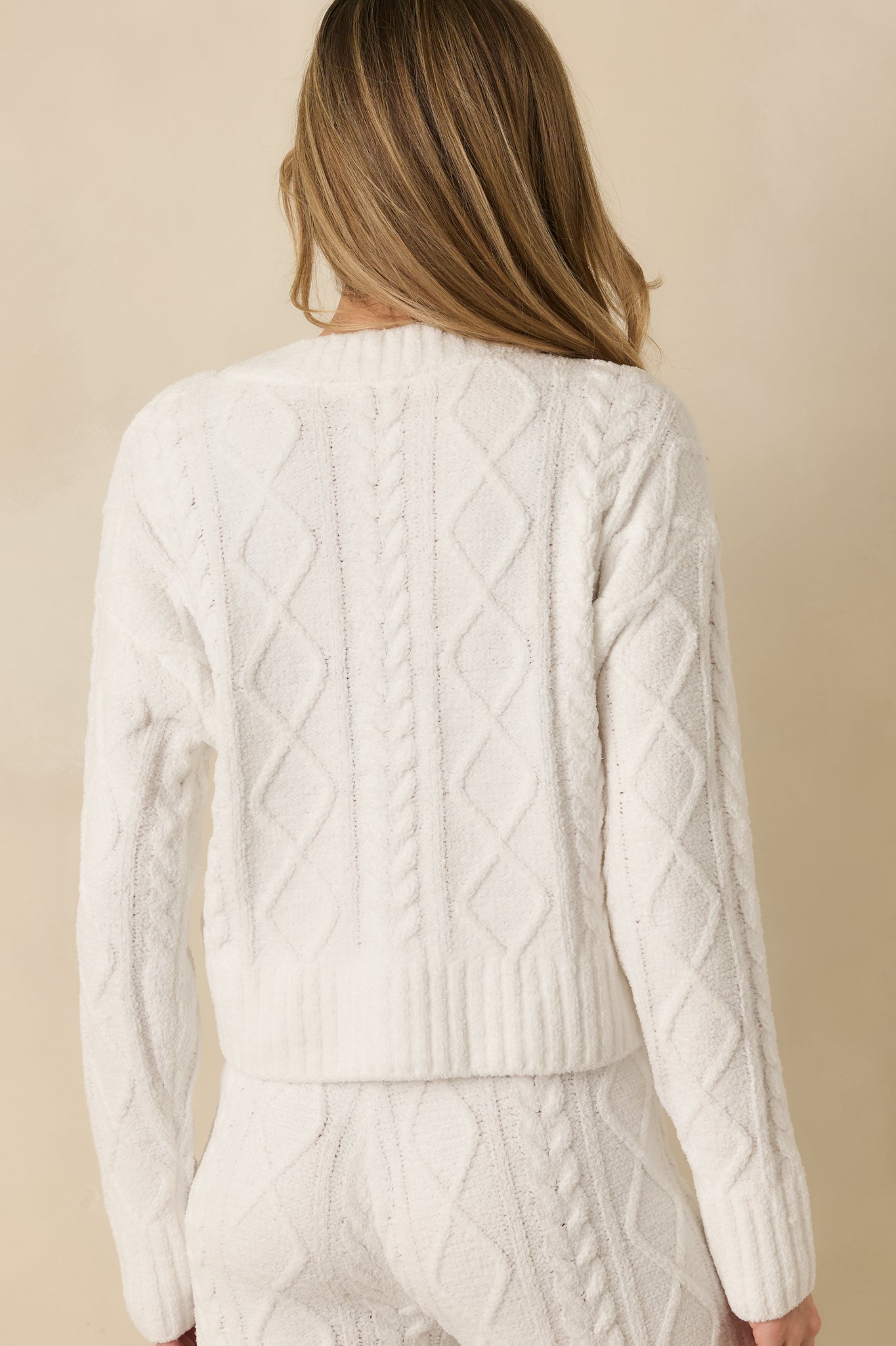 Back view of ivory cable knit cardigan showing smooth knit, long sleeves, and relaxed silhouette.