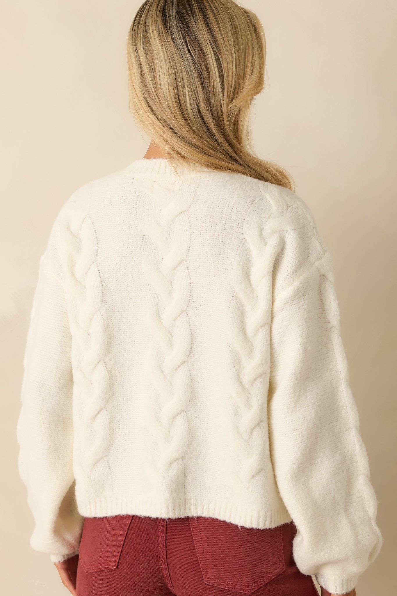 Rear view of ivory cable knit cardigan showing long sleeves, relaxed fit, and clean back detailing.