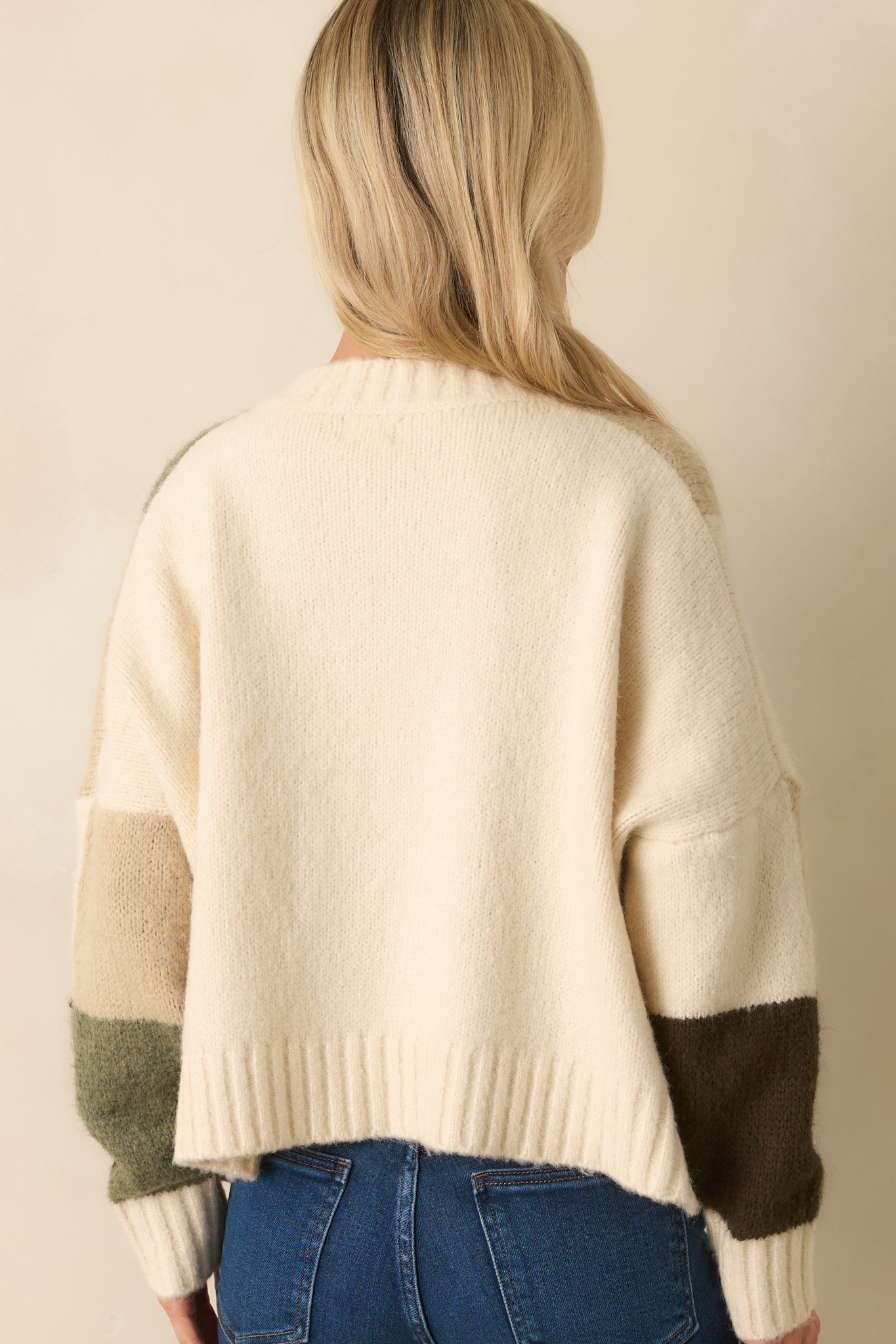 A back view of the knit cardigan capturing the clean ivory fabric and ribbed hem.