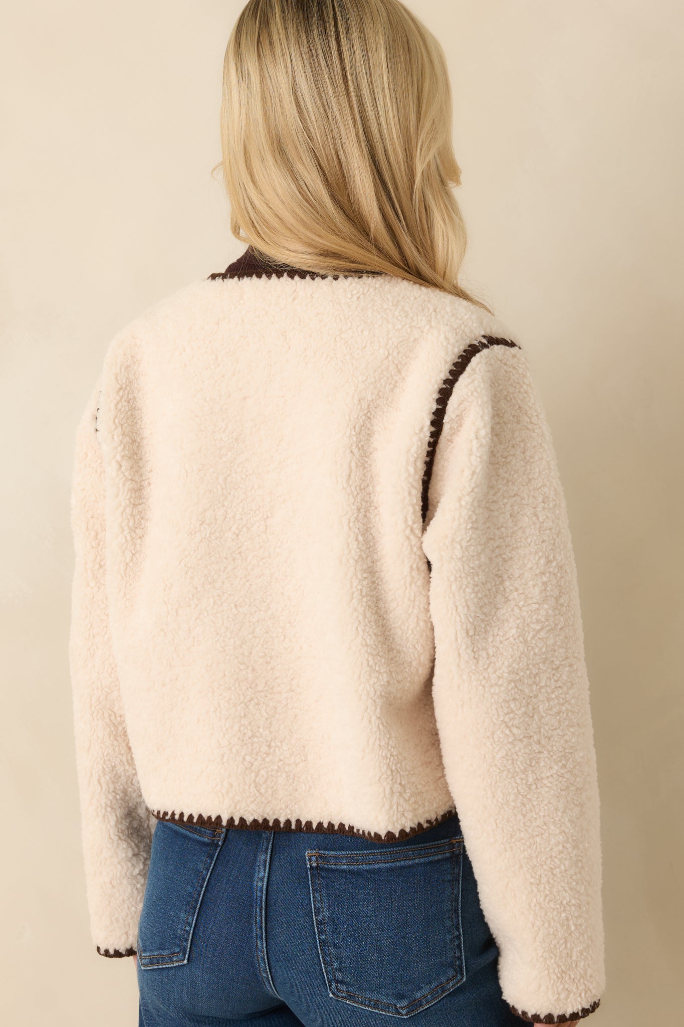 Back view of the ivory sherpa jacket displaying its relaxed silhouette and contrast edging.