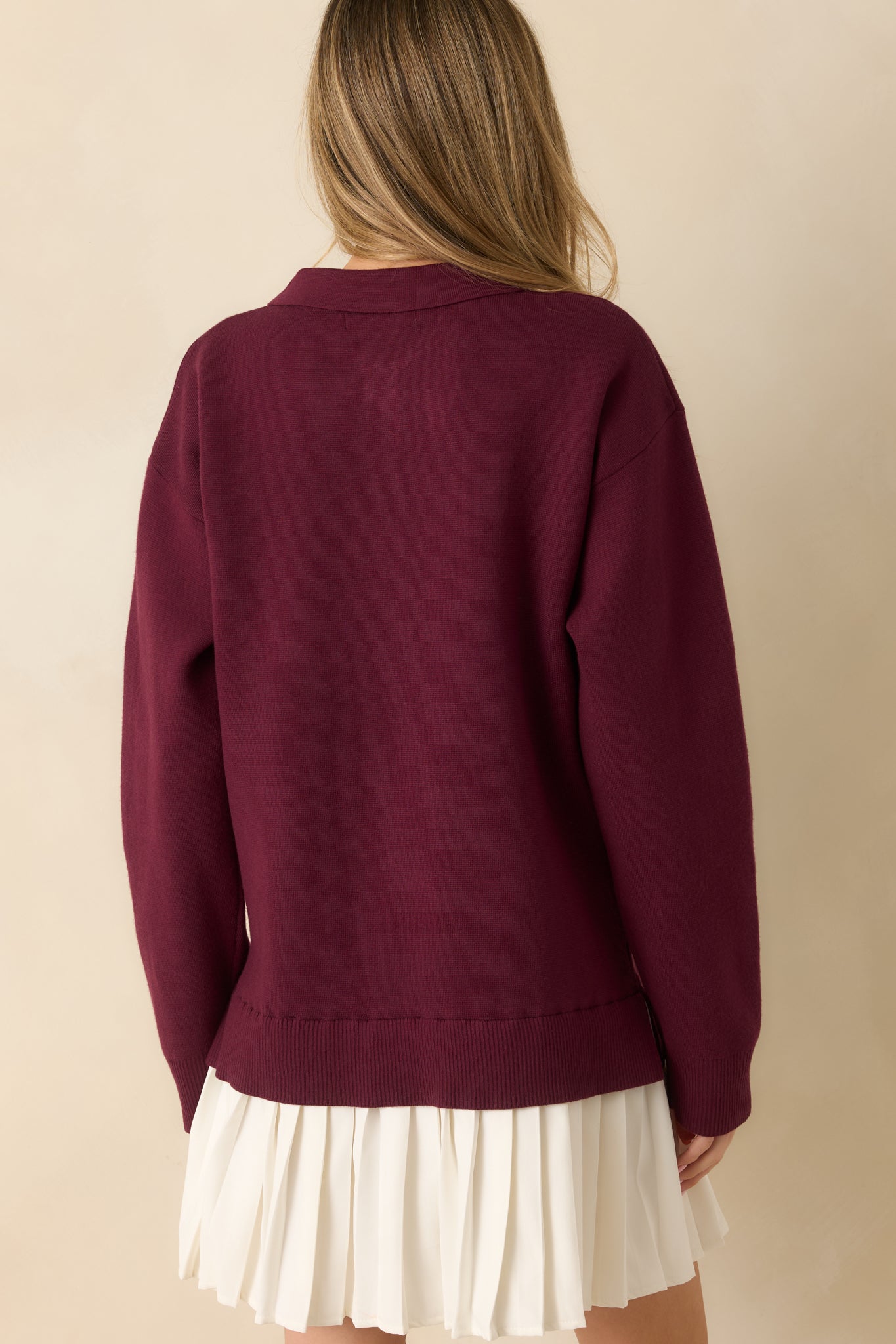 Back view showing smooth knit fabric, long sleeves, and ribbed hem on burgundy mini dress.