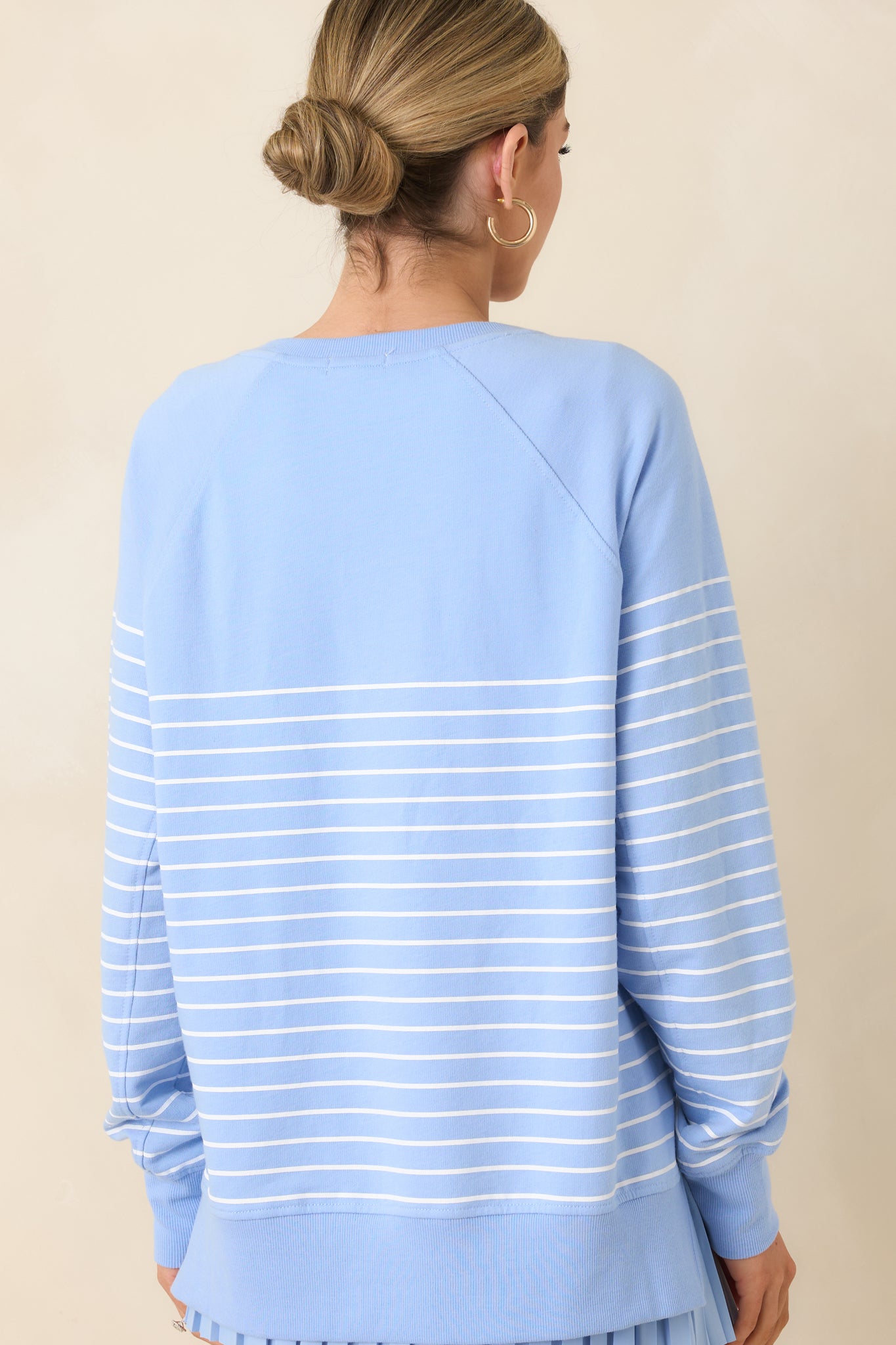 Back view of the light blue weekender top displaying oversized fit, long raglan sleeves, and horizontal stripe detailing across the back.