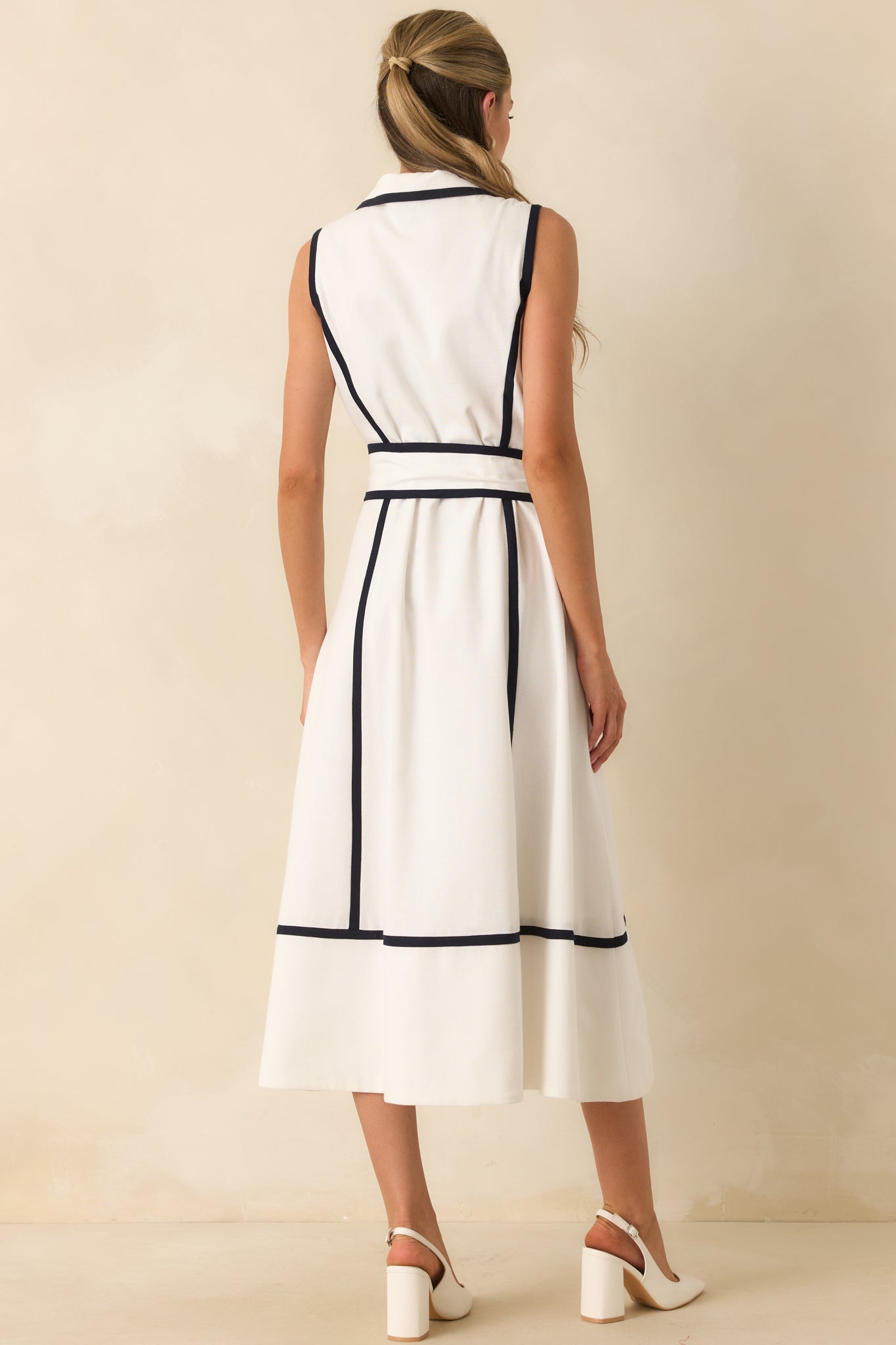 Back view of the sleeveless midi dress featuring a self-tie waist belt, fitted bodice, and full skirt silhouette.