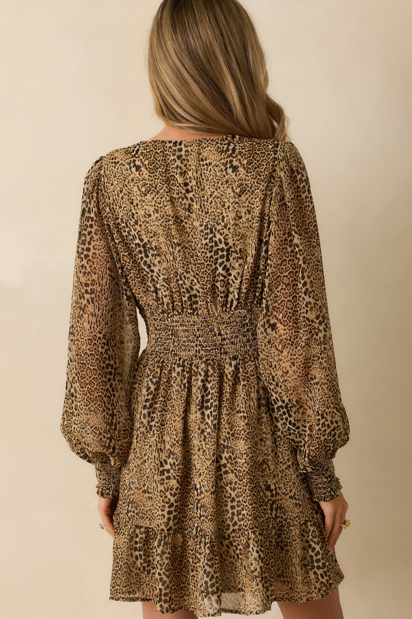 Rear view of the mini dress showing the smocked back insert, long balloon sleeves, and ruffled skirt finish.