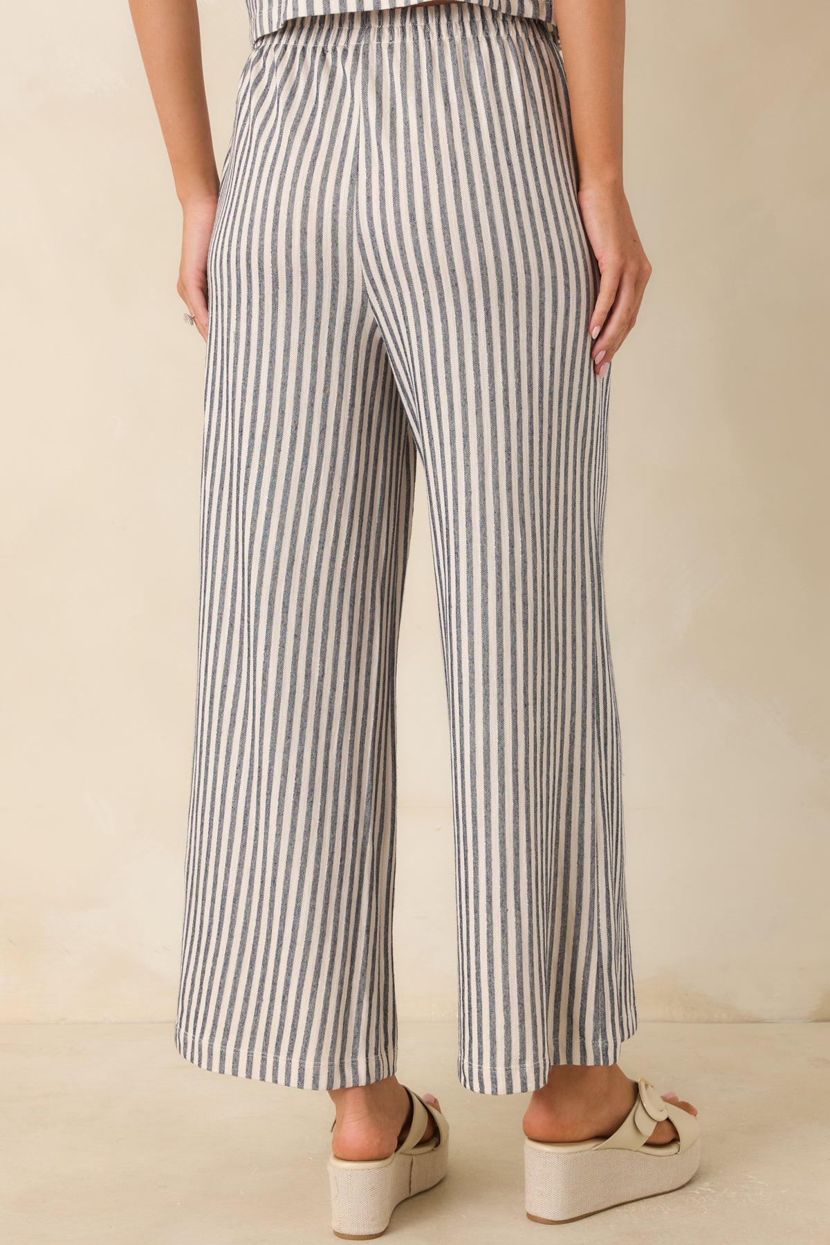 Back view of navy and ivory striped knit pants featuring a relaxed wide leg silhouette.
